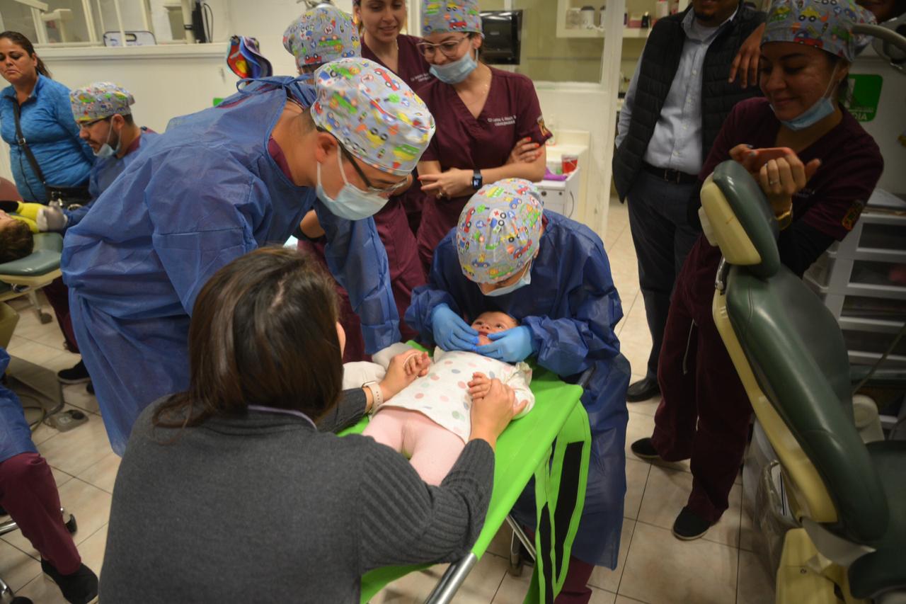 Bebé en camita especial recibiendo atención odontológica con participación de la mamá