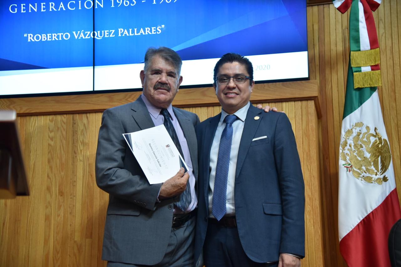 Graduado posando para la foto con el rector mostrando su constancia