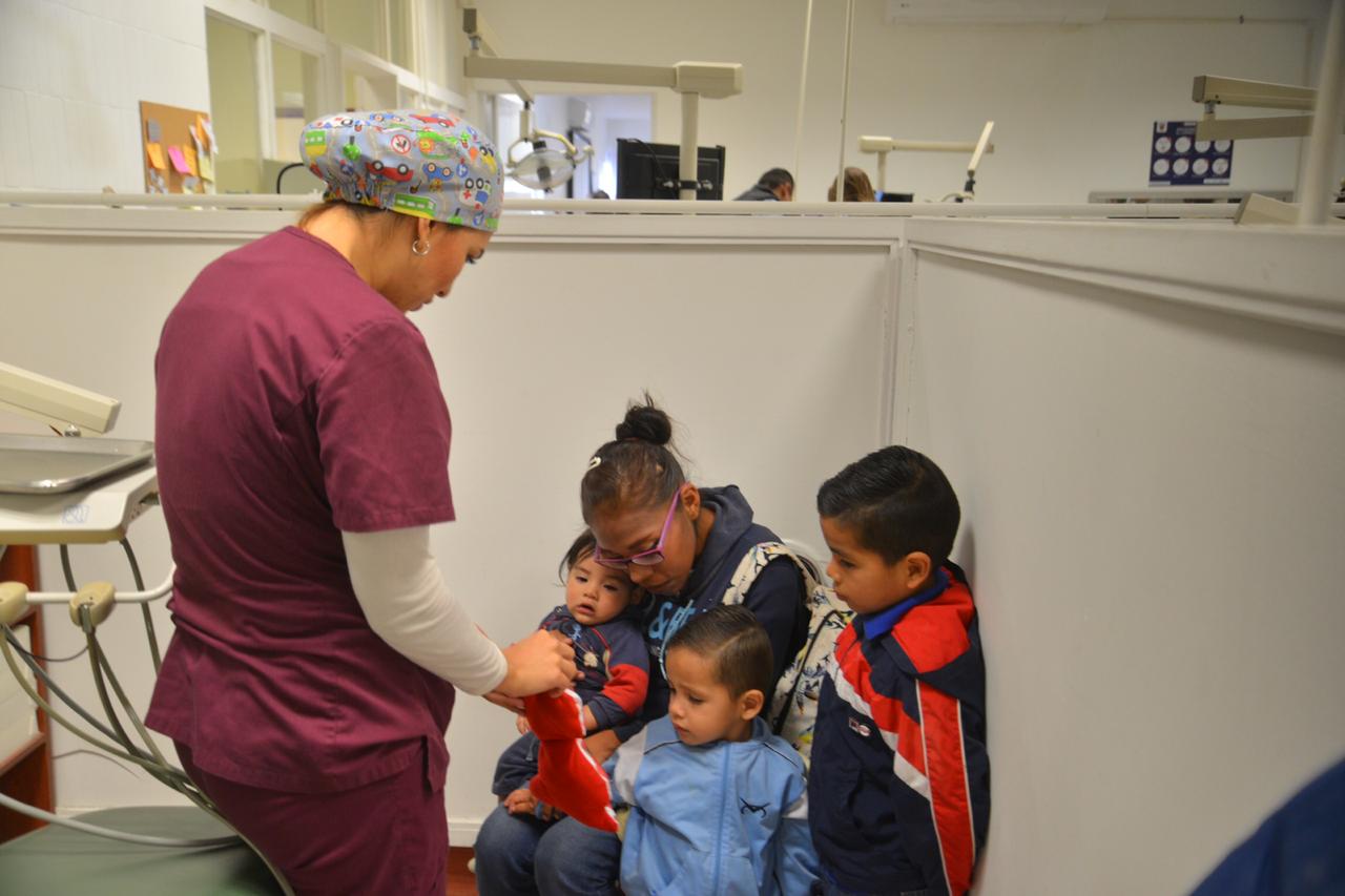 Especialista orientando a mamá y a sus hijos en técnicas de cepillado con apoyo de un mono de peluche