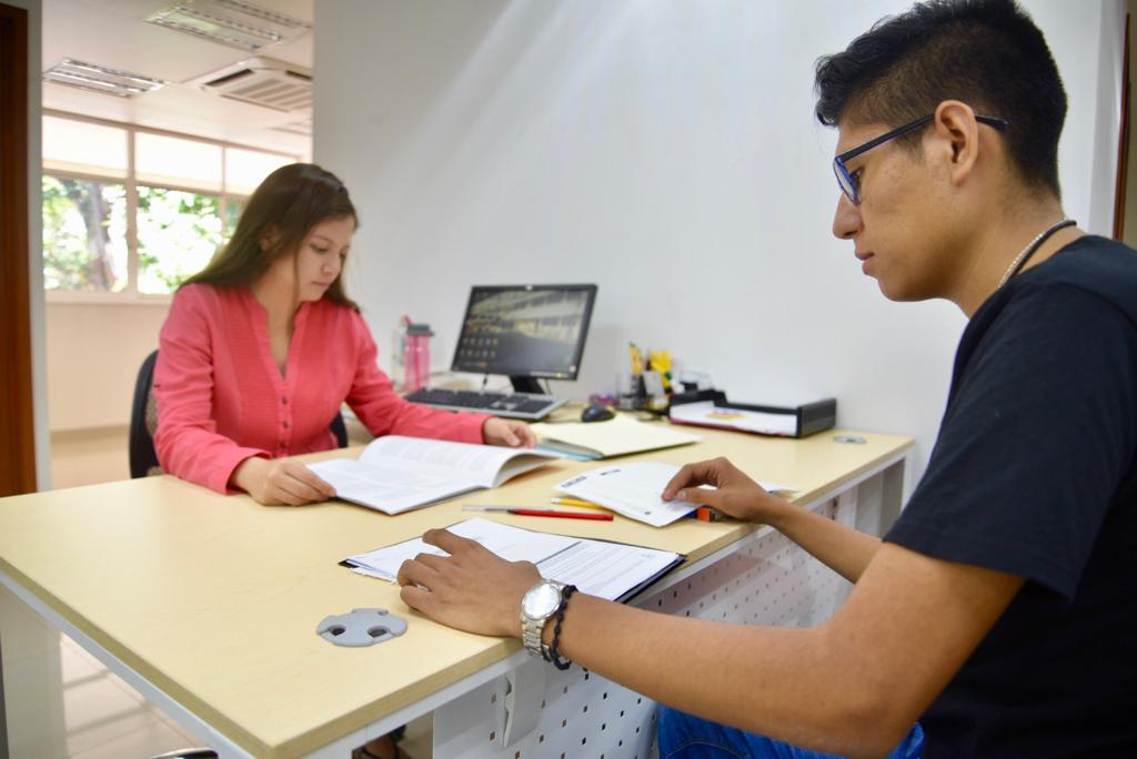 Alumnos del CUCS revisando documentos en un escritorio