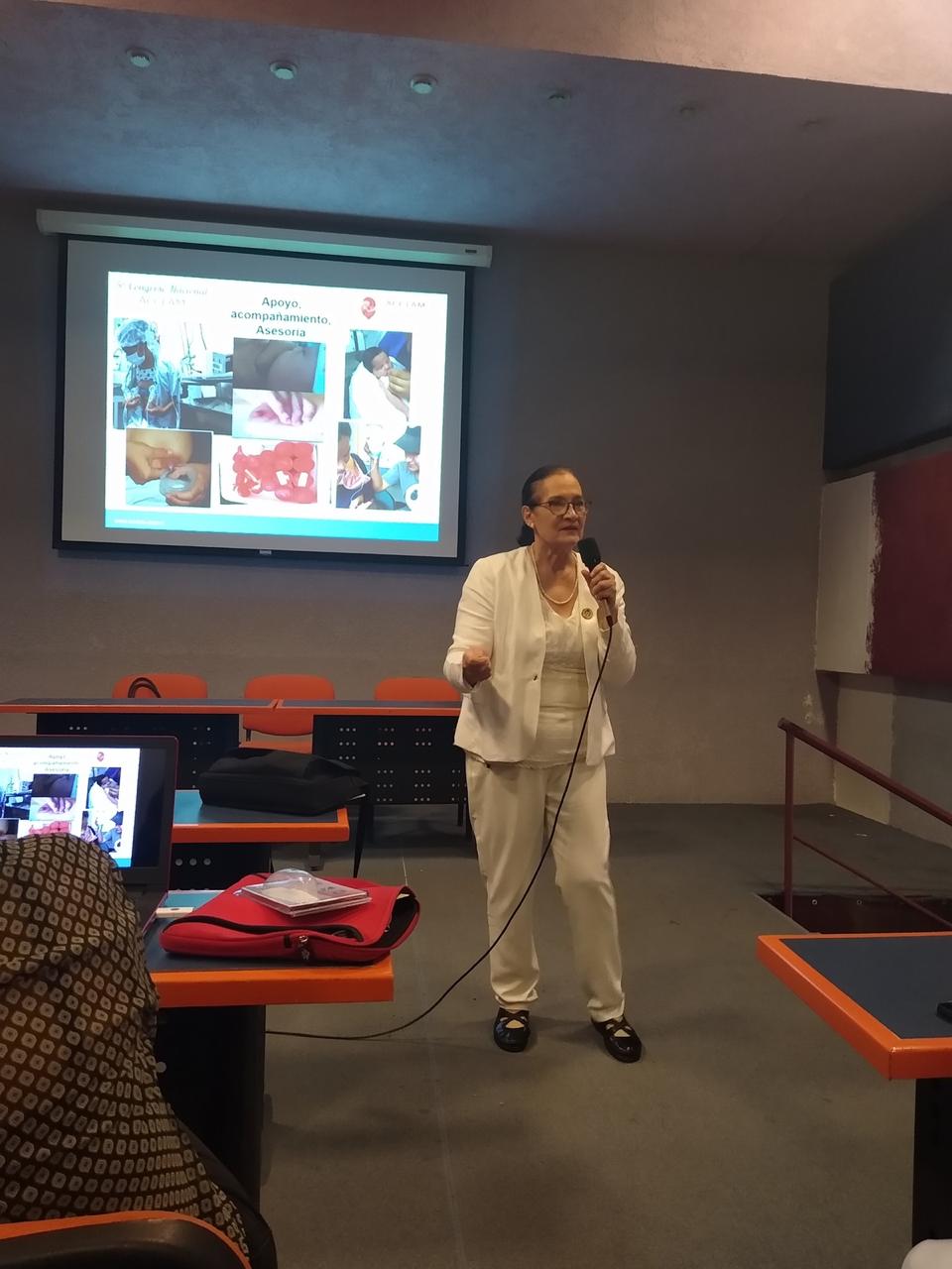 Ponente explicando una diapositiva al frente del auditorio