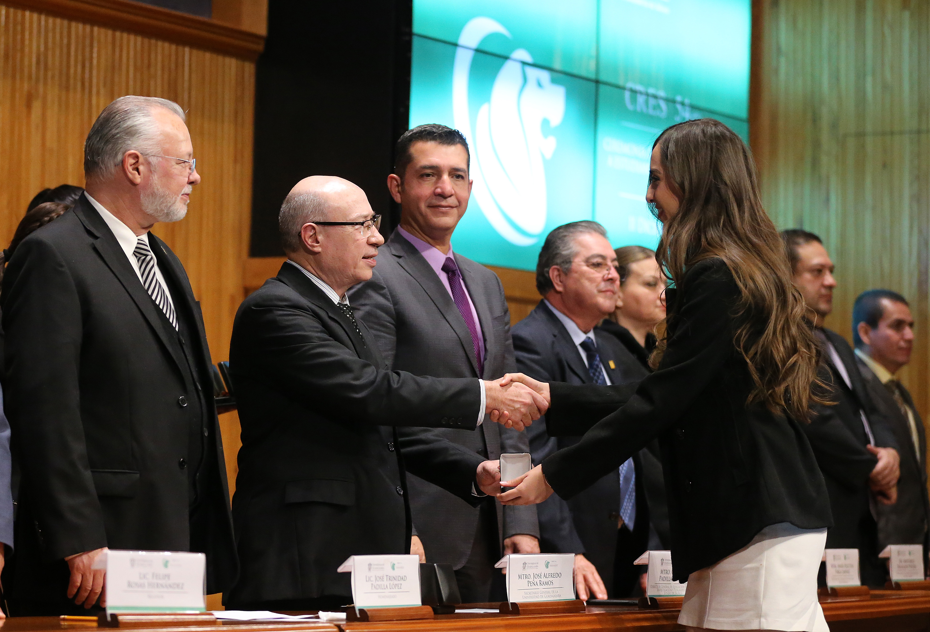 Alumna reconocidos saludando a los miembros del presídium
