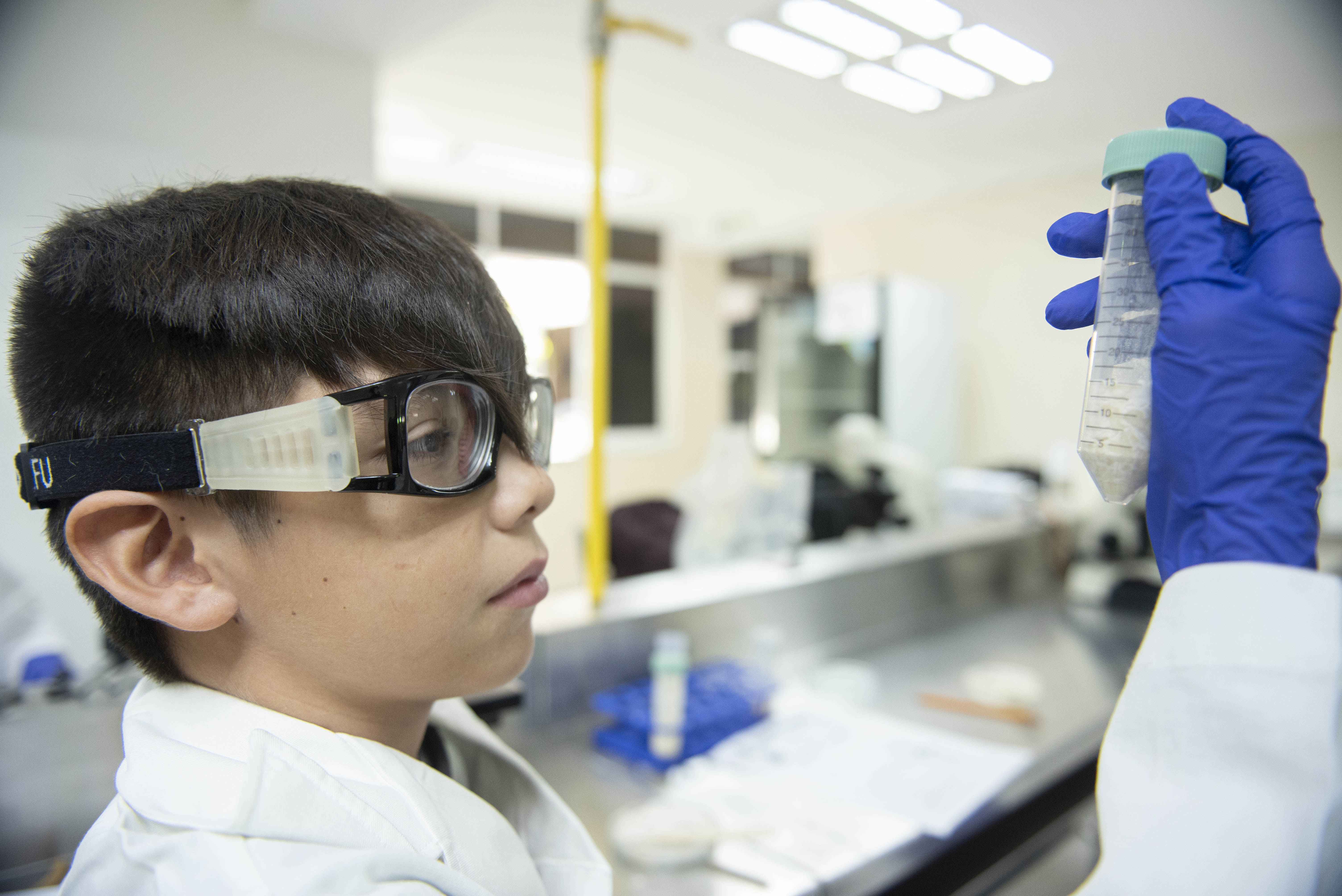 Niño con altas capacidades levantando un probeta al tiempo que la observa