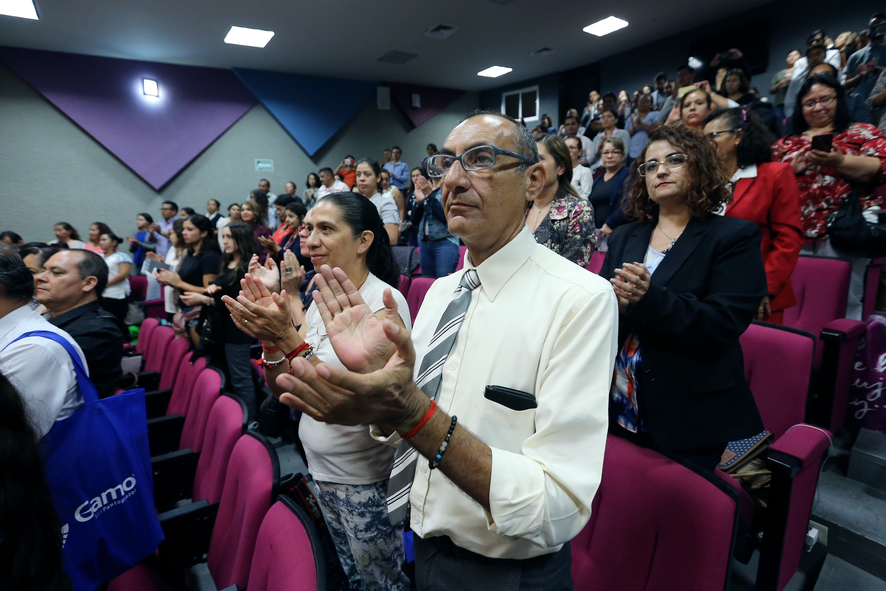 Asistentes de pie aplaudiendo tras el acto inaugural