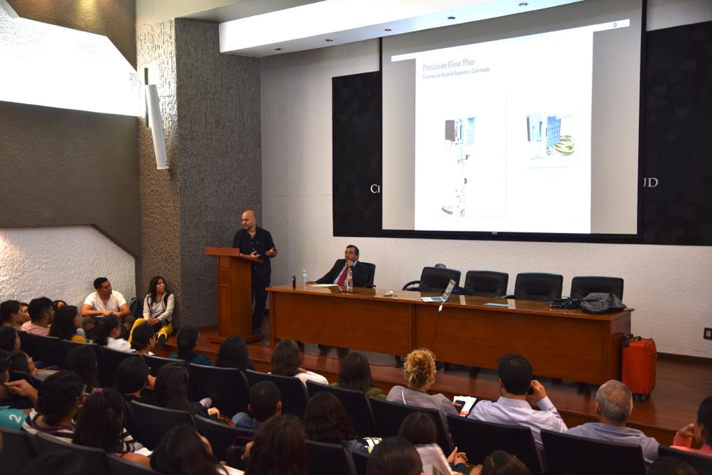 Toma desde atrás del auditorio, al fondo el ponente y una diapositiva en la pantalla