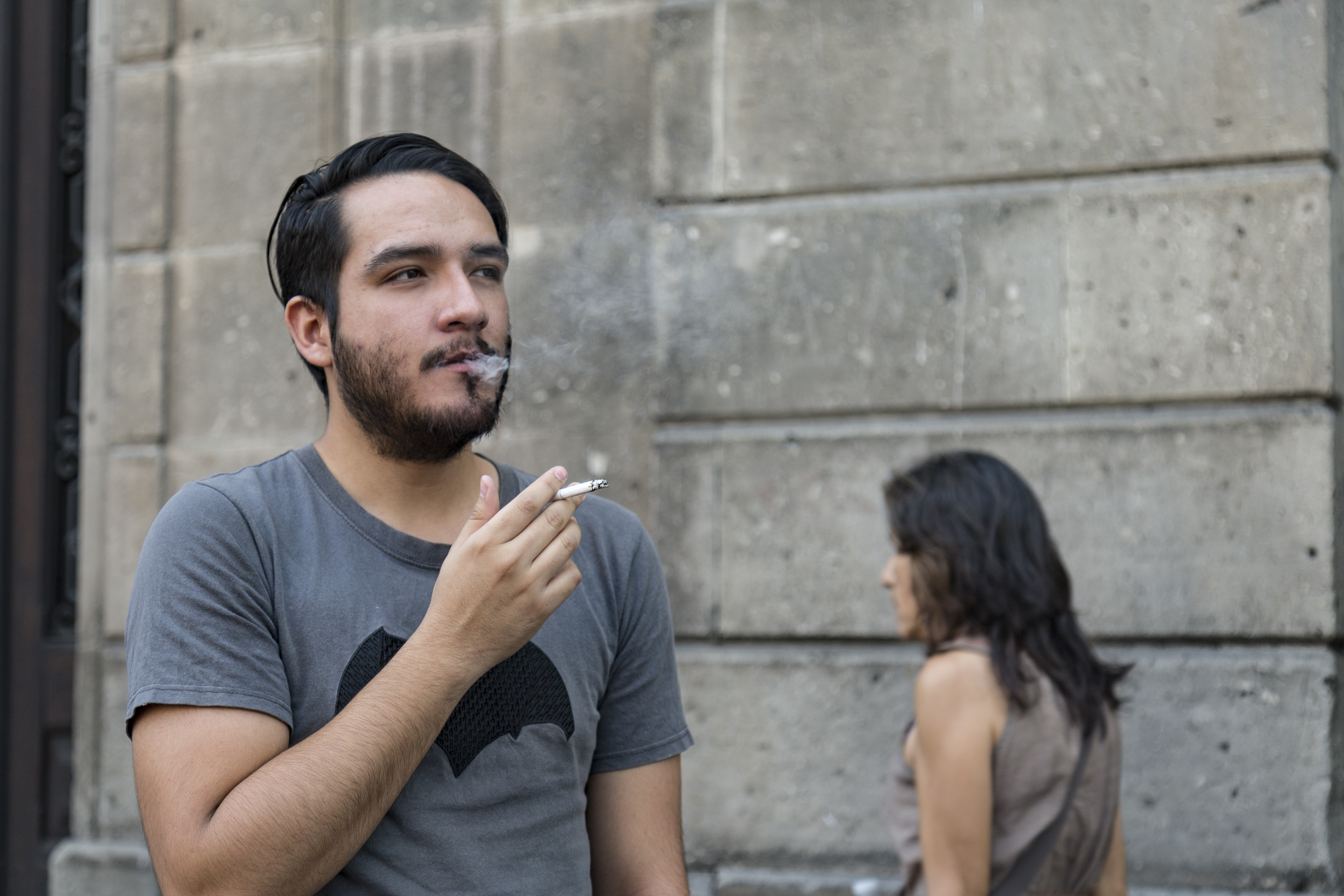 Joven fumando al ir caminando por la calle