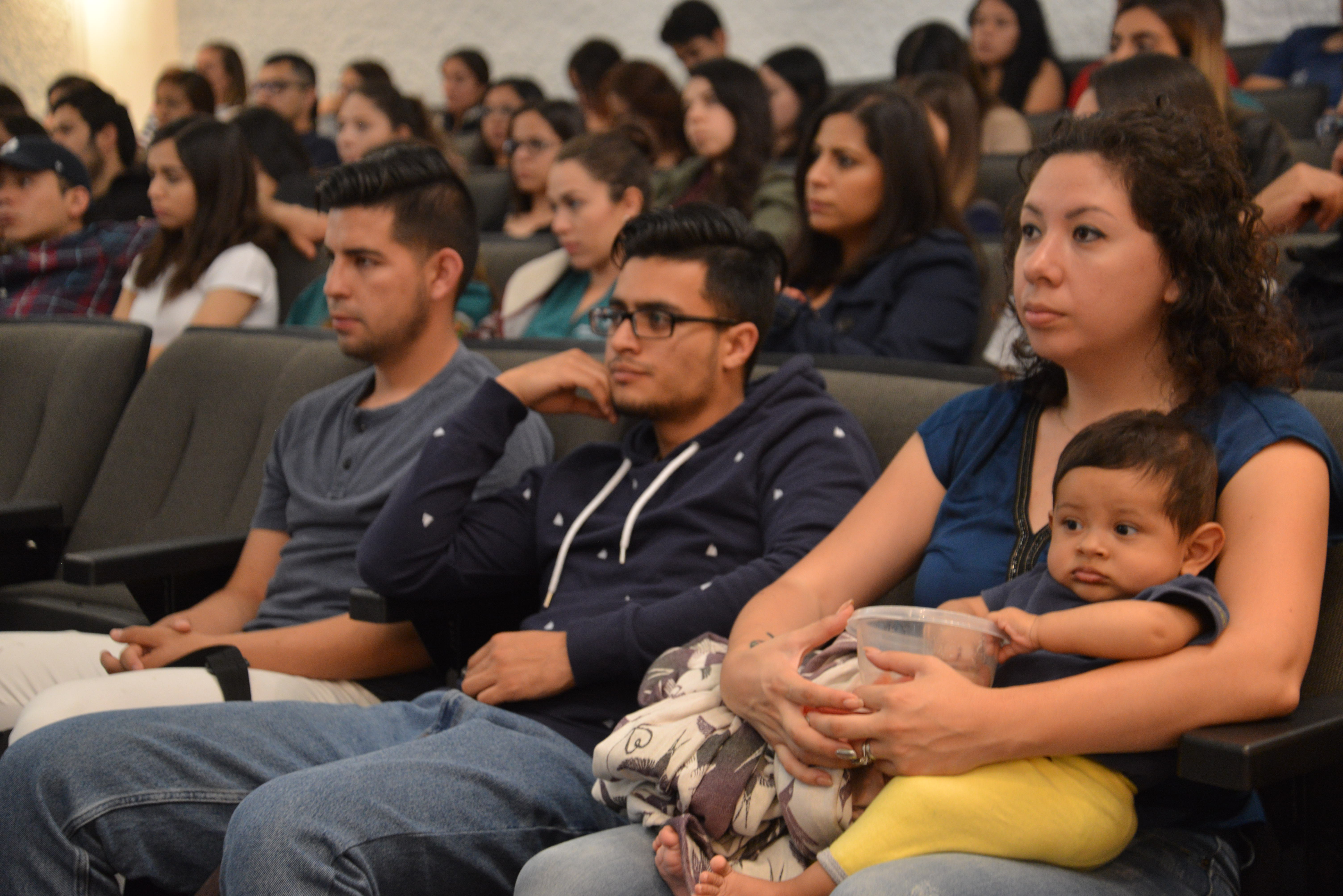 Mamá con su hijo en brazos escuchando la conferencia