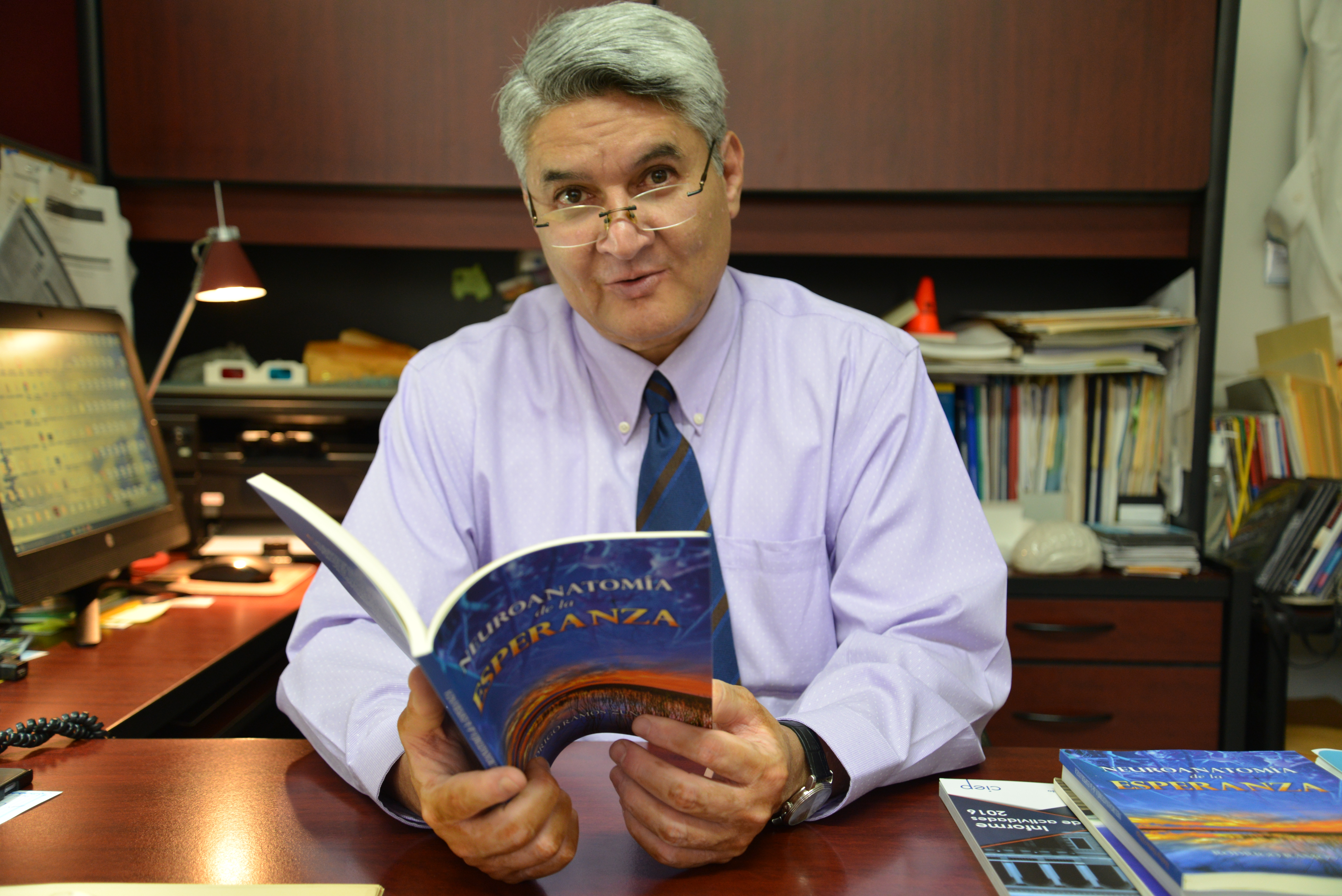 Dr. Rodrigo Ramos con su libro abierto en las manos y sonriendo