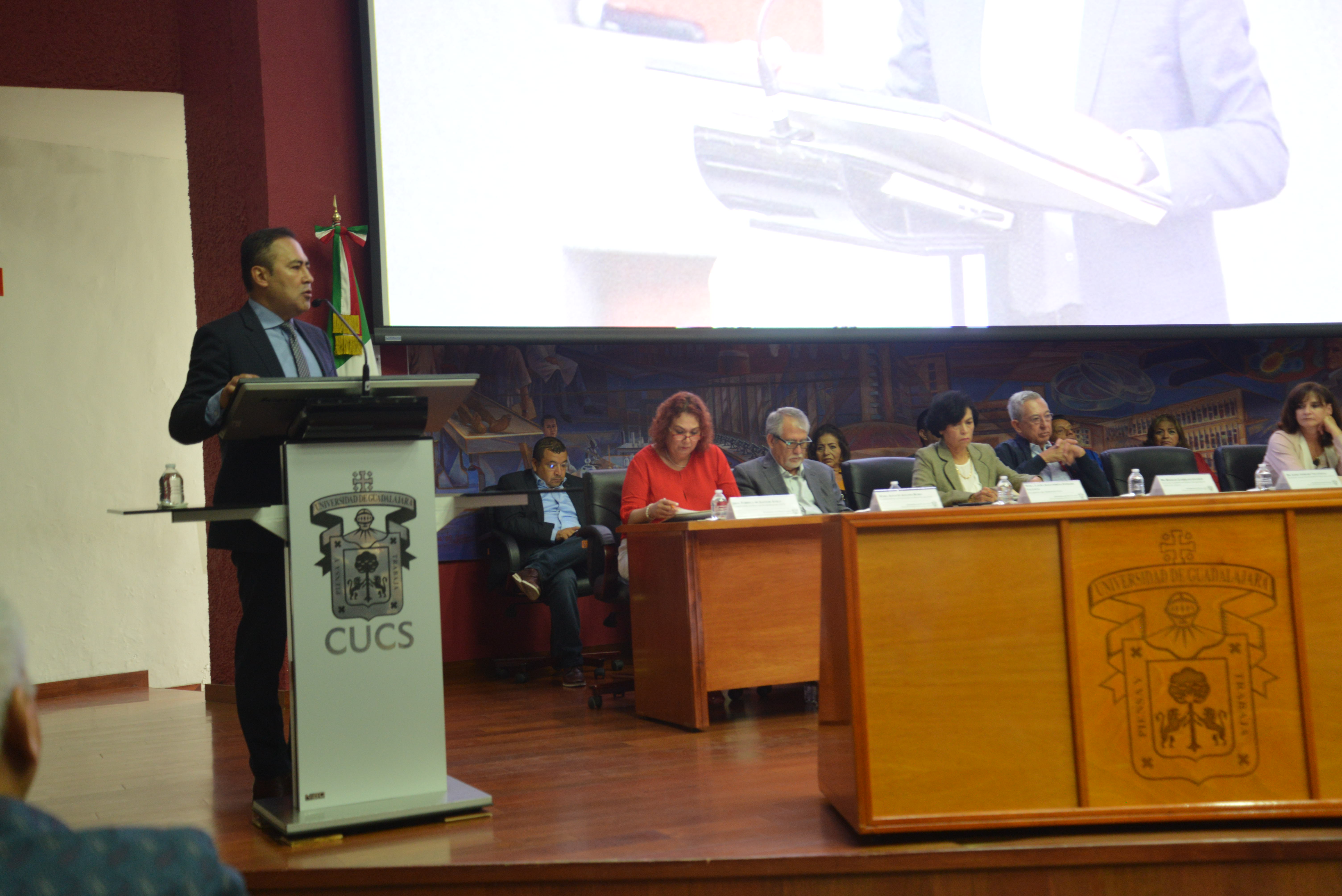 Rector de CUCS al podio exponiendo ante padres de familia