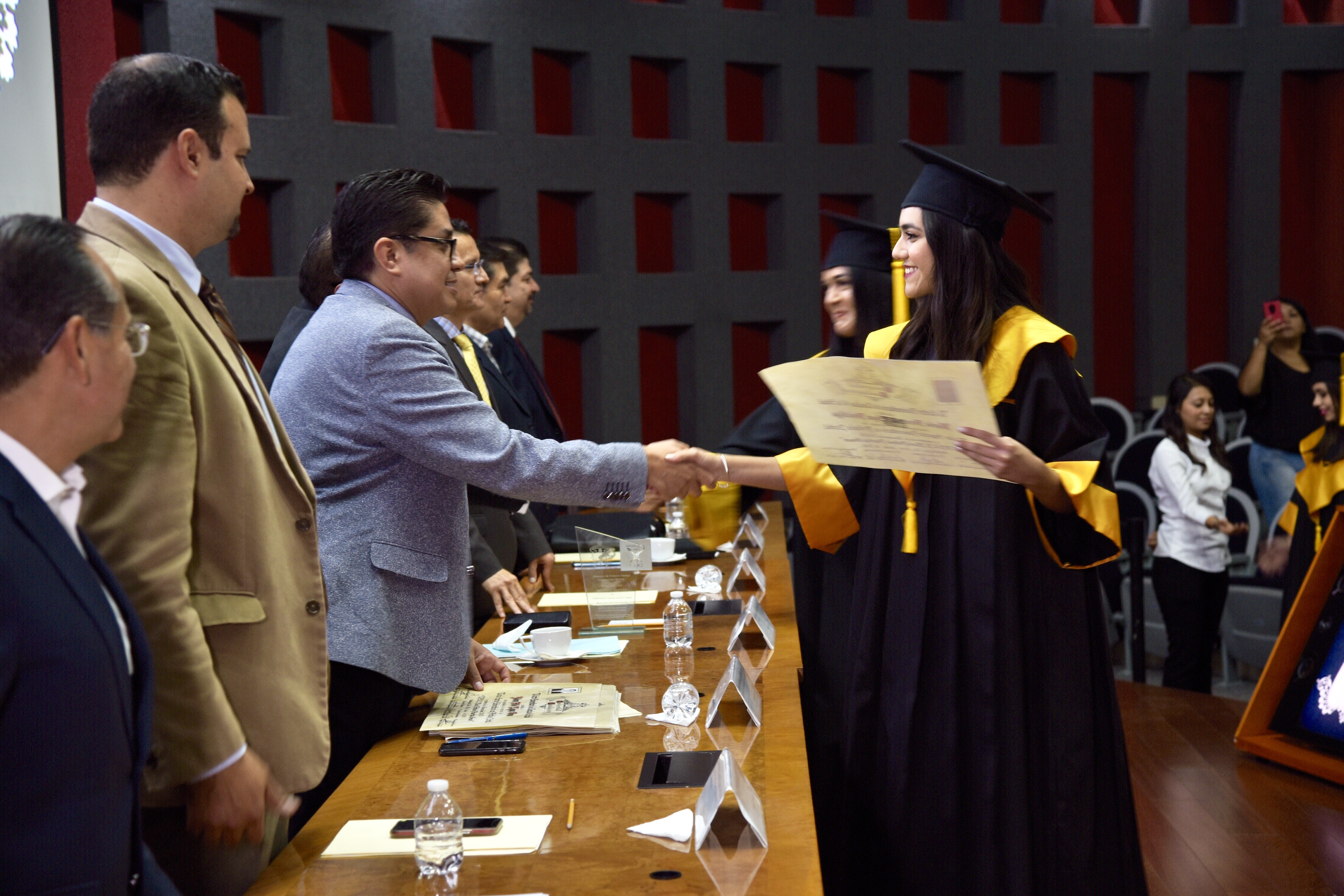 Rector del CUCS entregando constancia de egresado a graduada