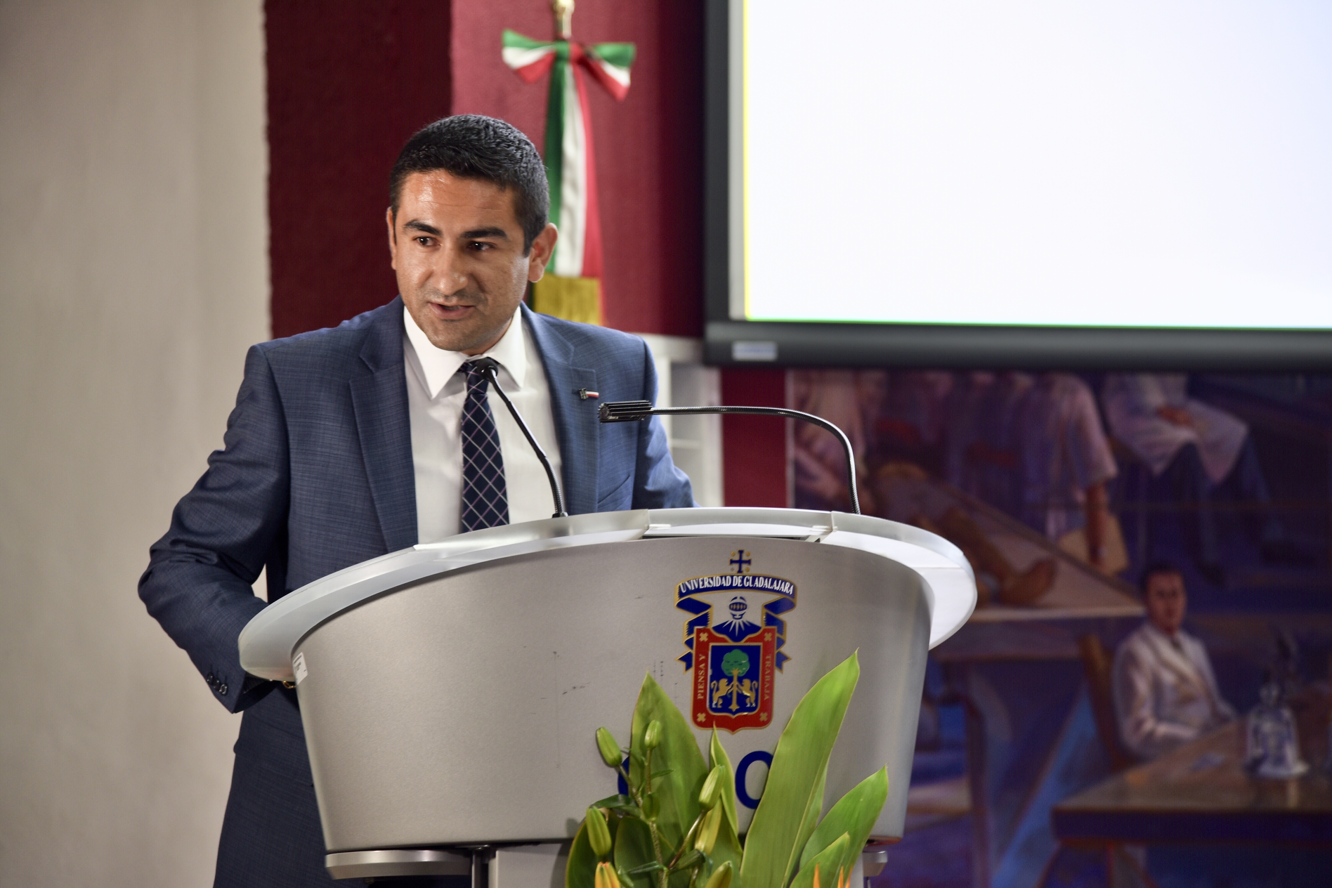 Coordinador de la carrera ofreciendo mensaje a graduados