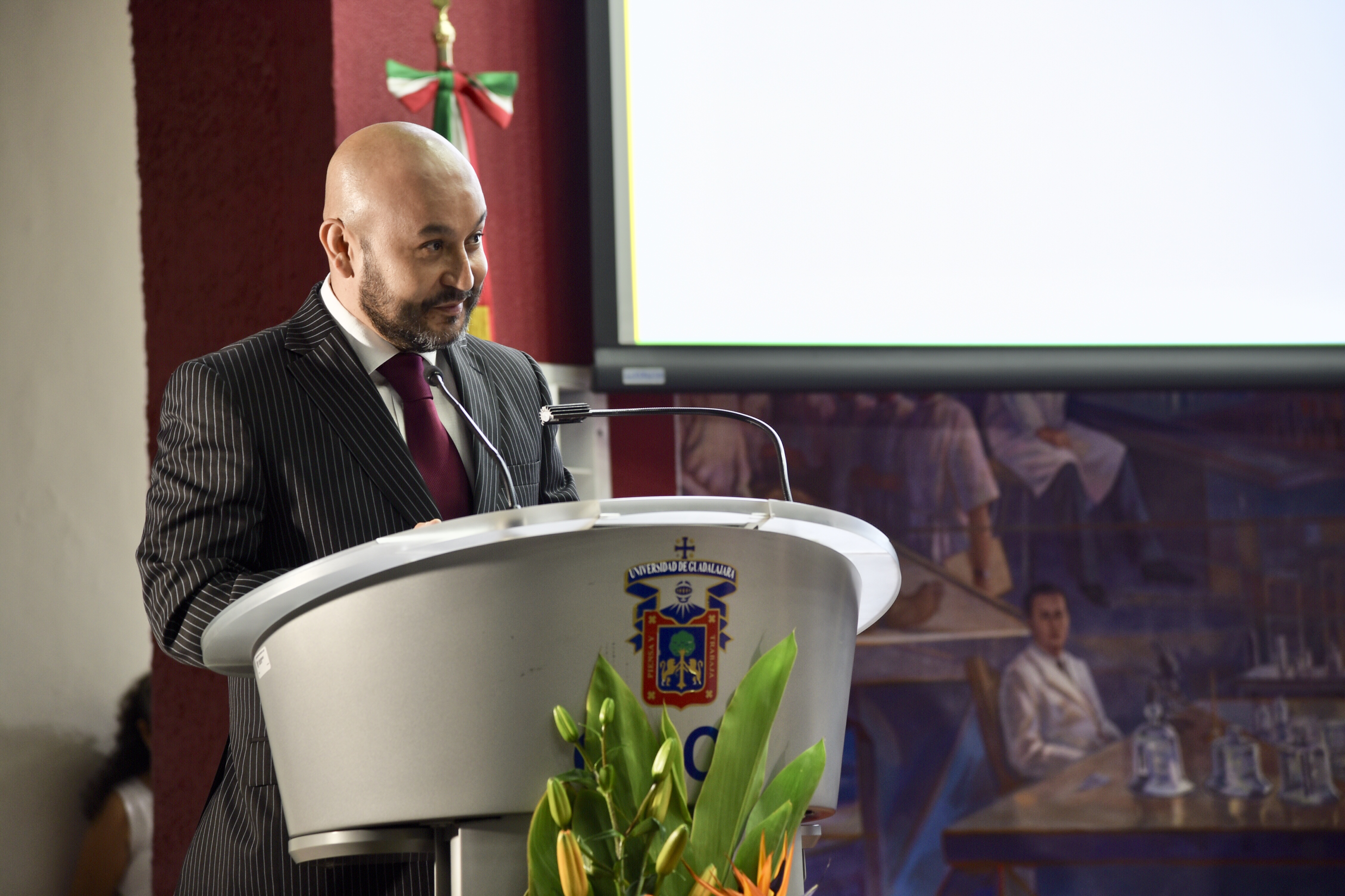 Padrino de Generación en pódium dirigiendo mensaje a graduados
