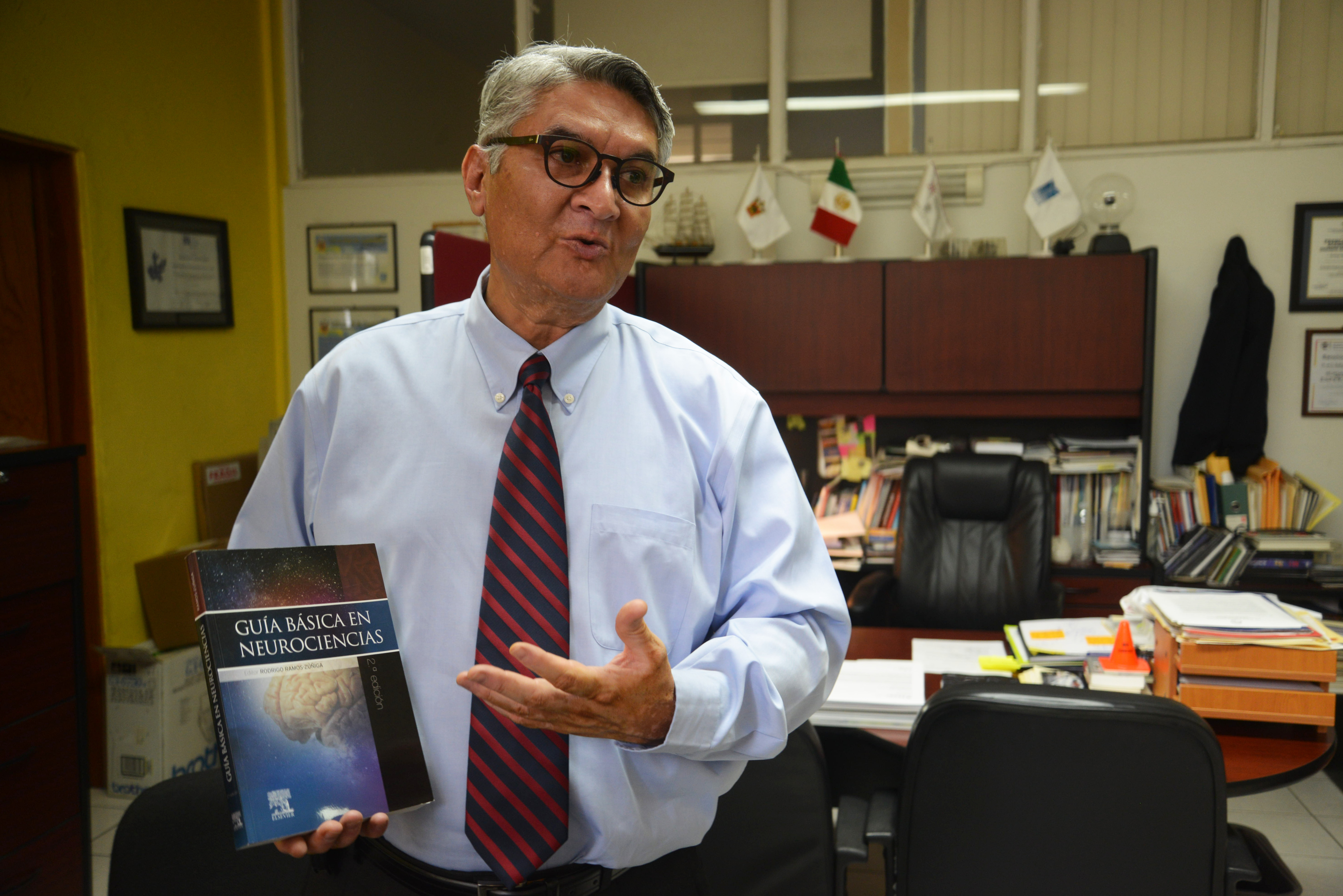 Dr. Rodrigo Ramos exhibe el libro durante la entrevista