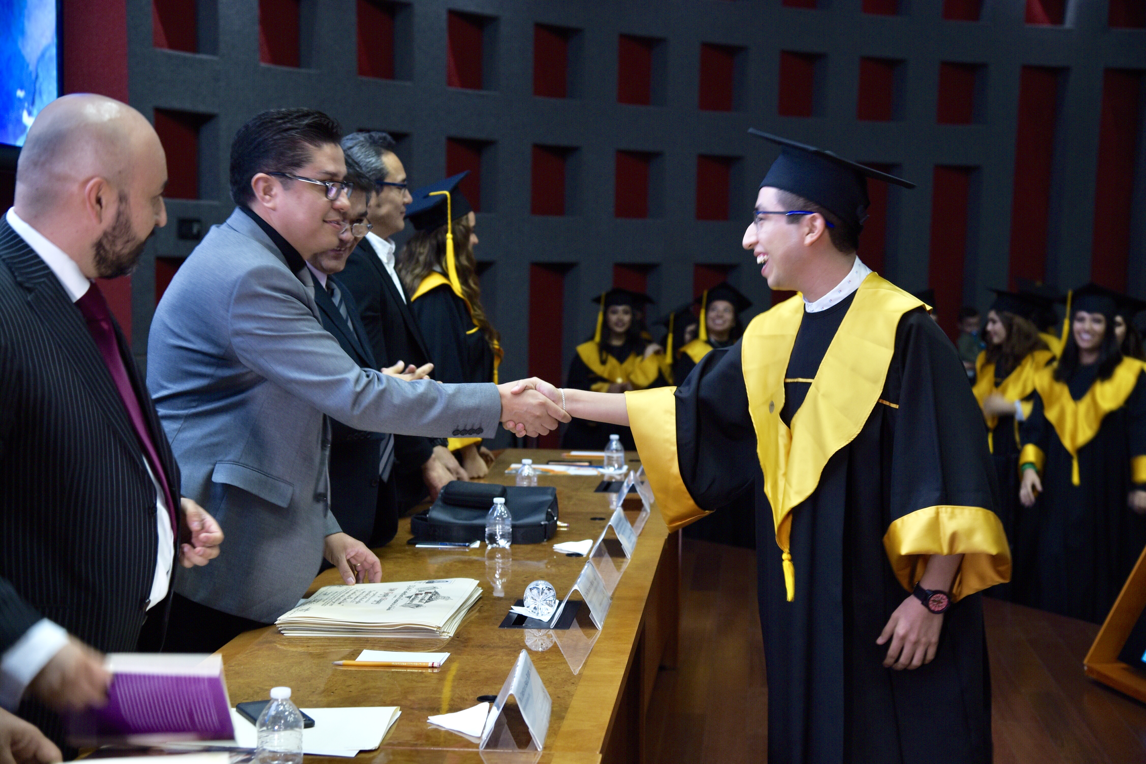 Rector entregando carta a graduado saludándolo de mano