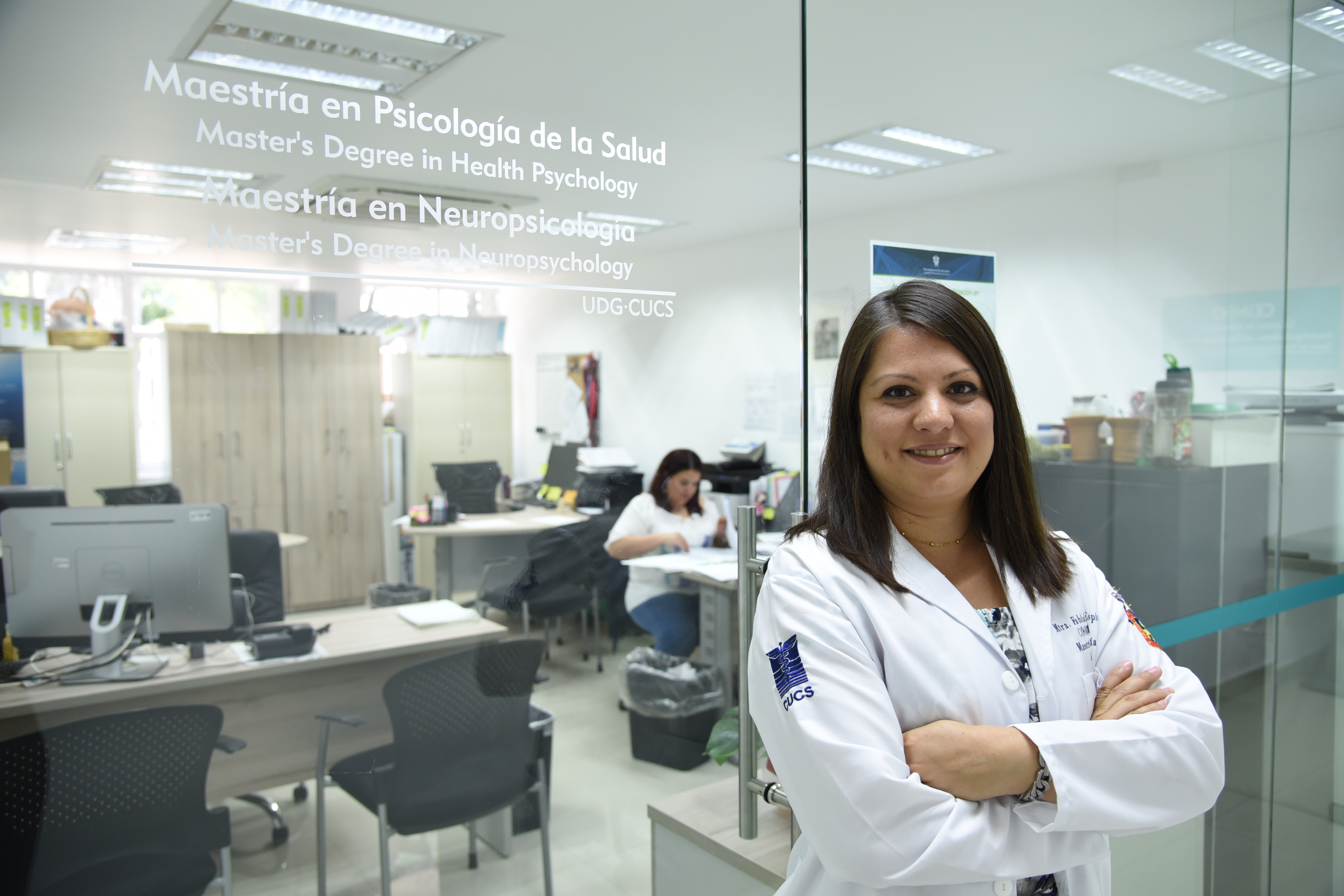 Coordinadora de la Maestría en Psicología de la Salud, atrás letrero de la oficina de la coordinación