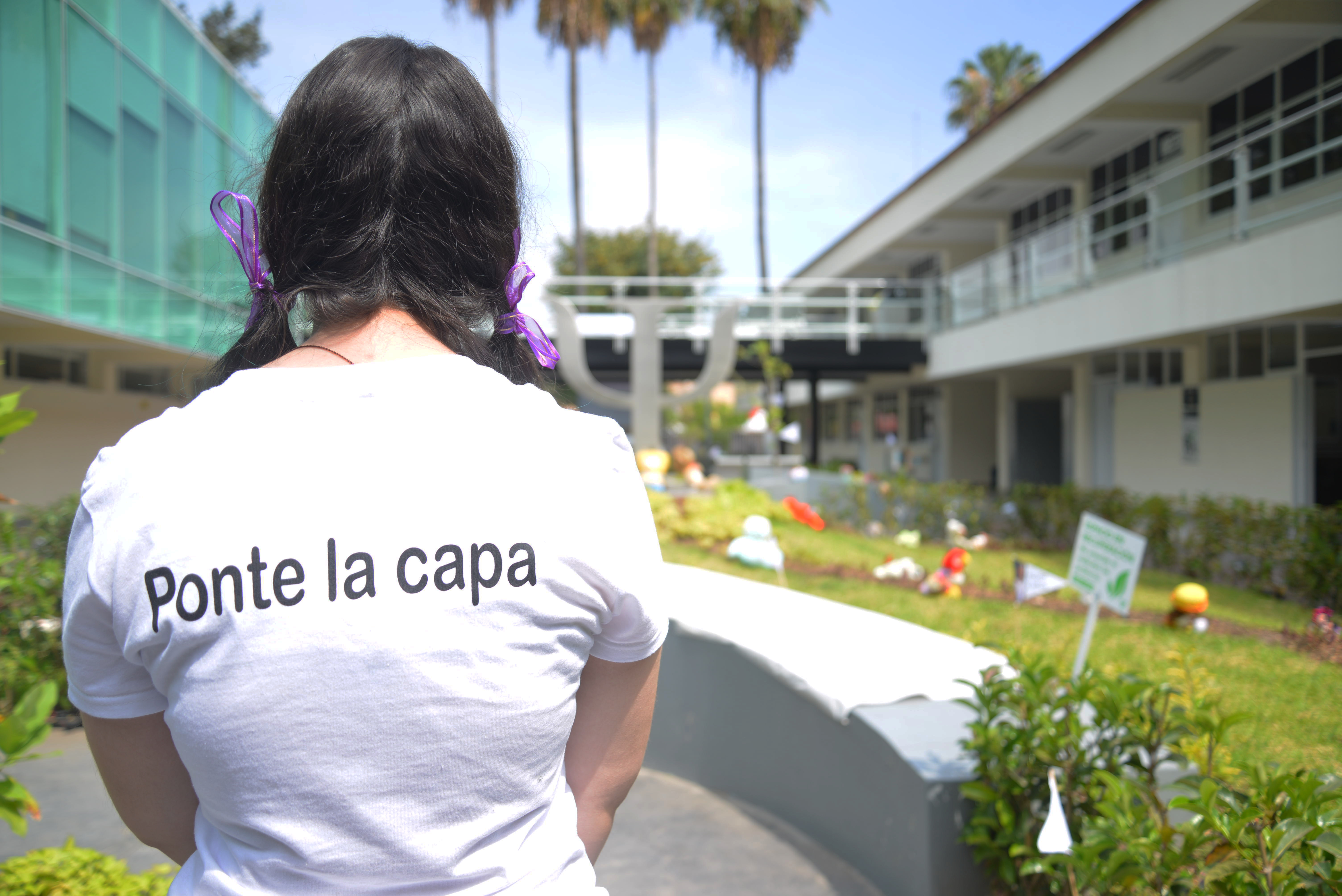 Alumna exhibiendo playera con leyenda a la espalda "ponte la capa"