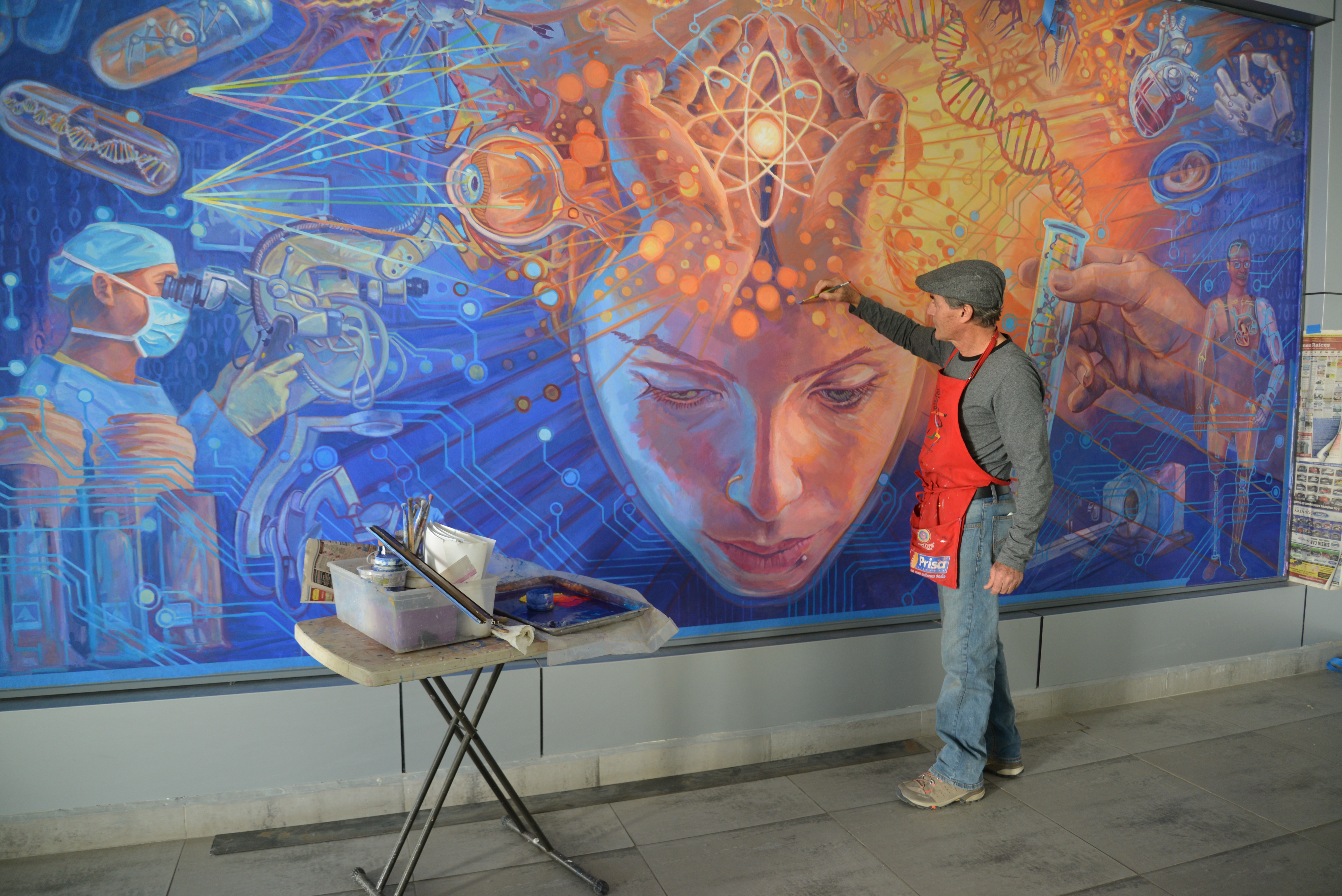 Vista general del mural del pintor Jorge Monrroy. Él de espaldas detallando su mural