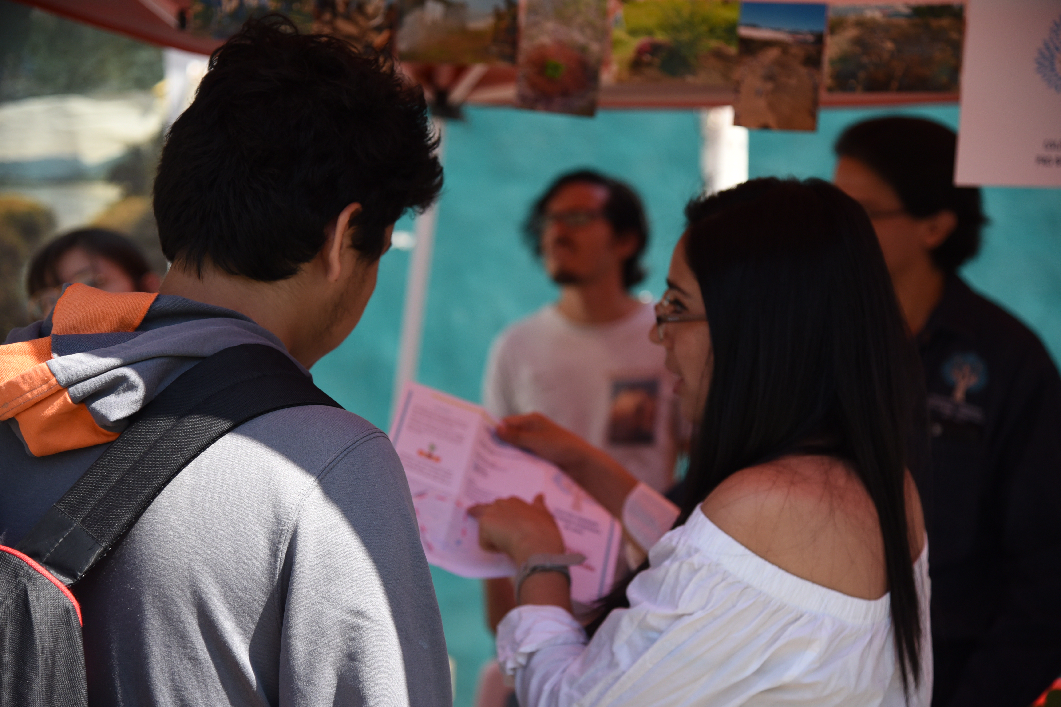 Responsable de stand mostrando un folleto a un alumno