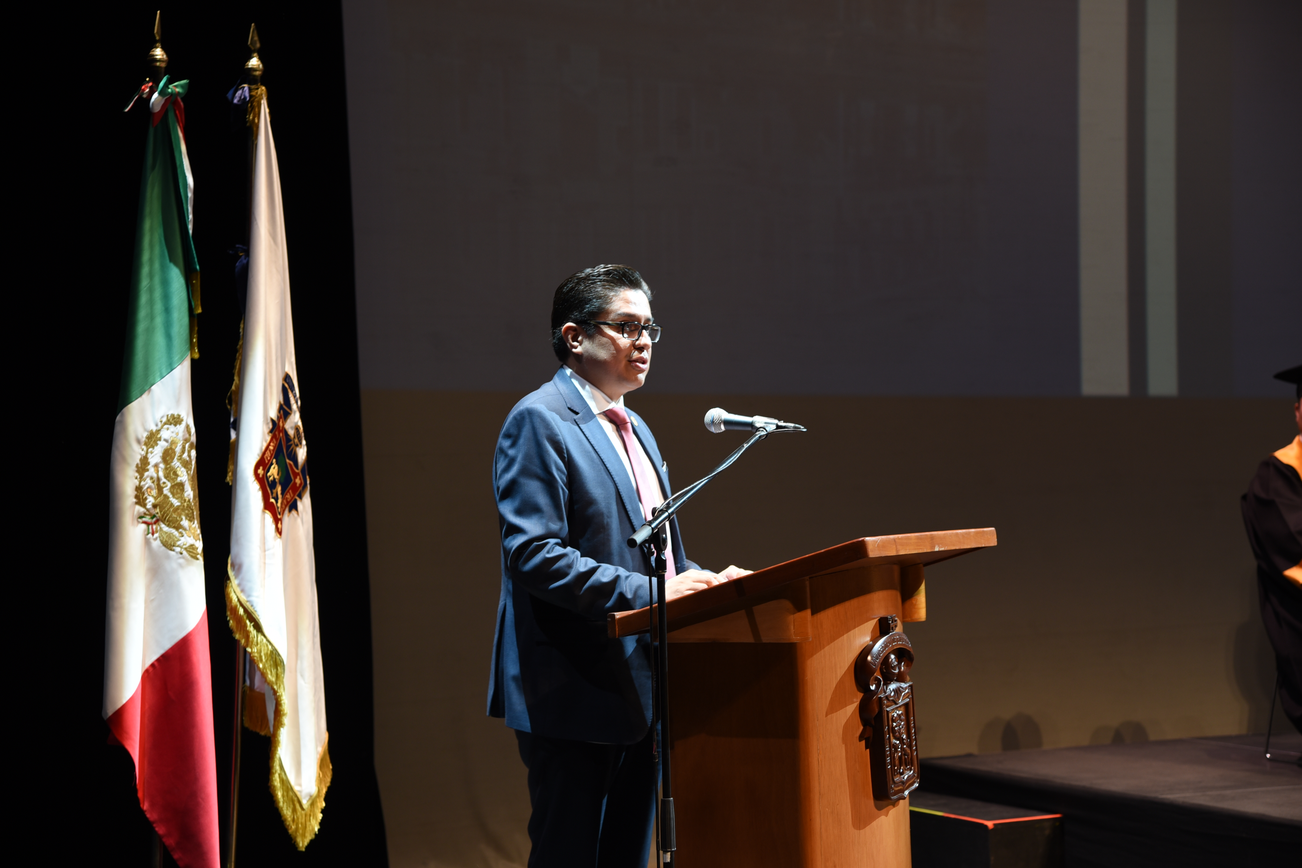Rector CUCS ofreciendo mensaje a graduados en el pódium