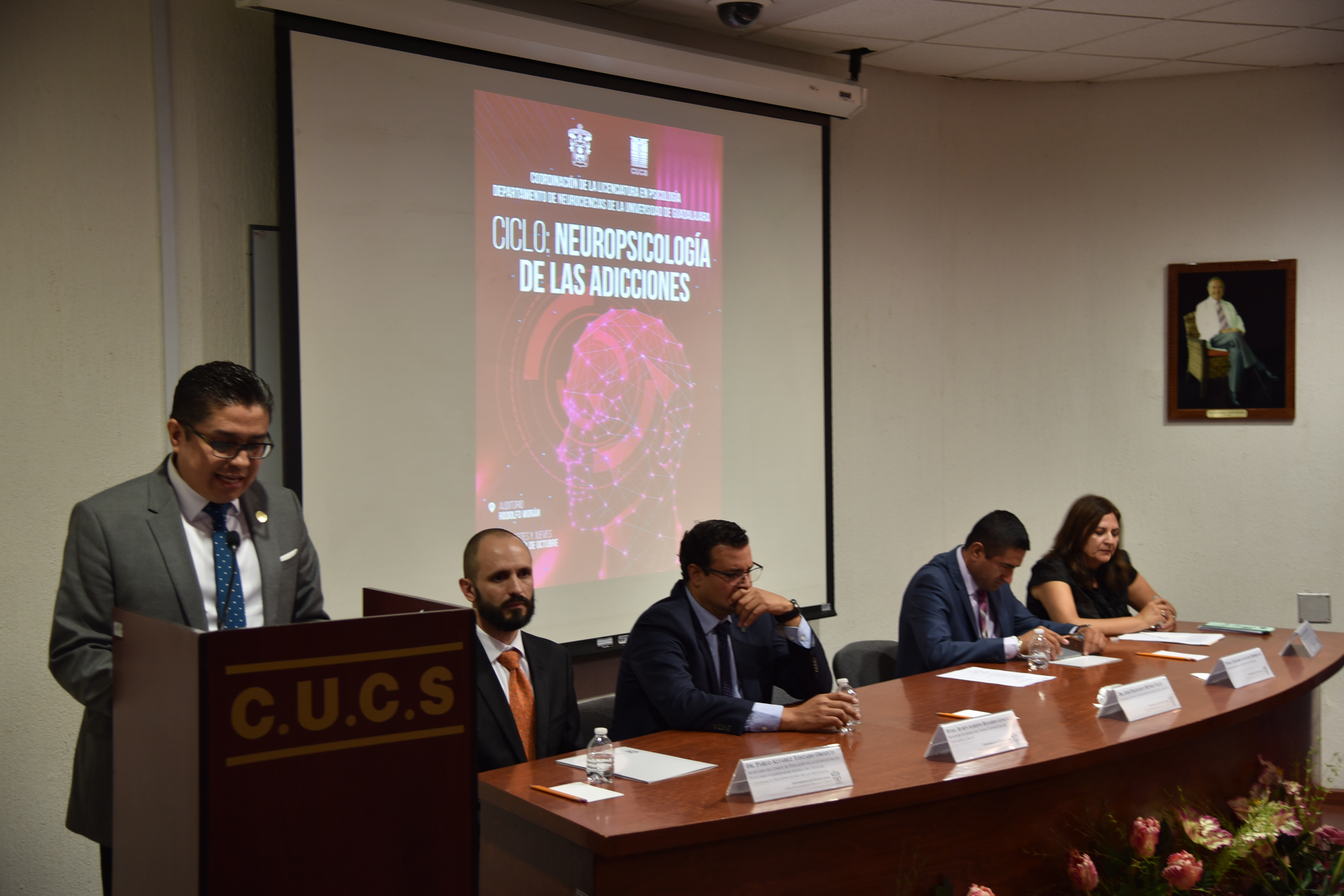 Rector del CUCS al micrófono en el podio, al fondo los miembros del presídium