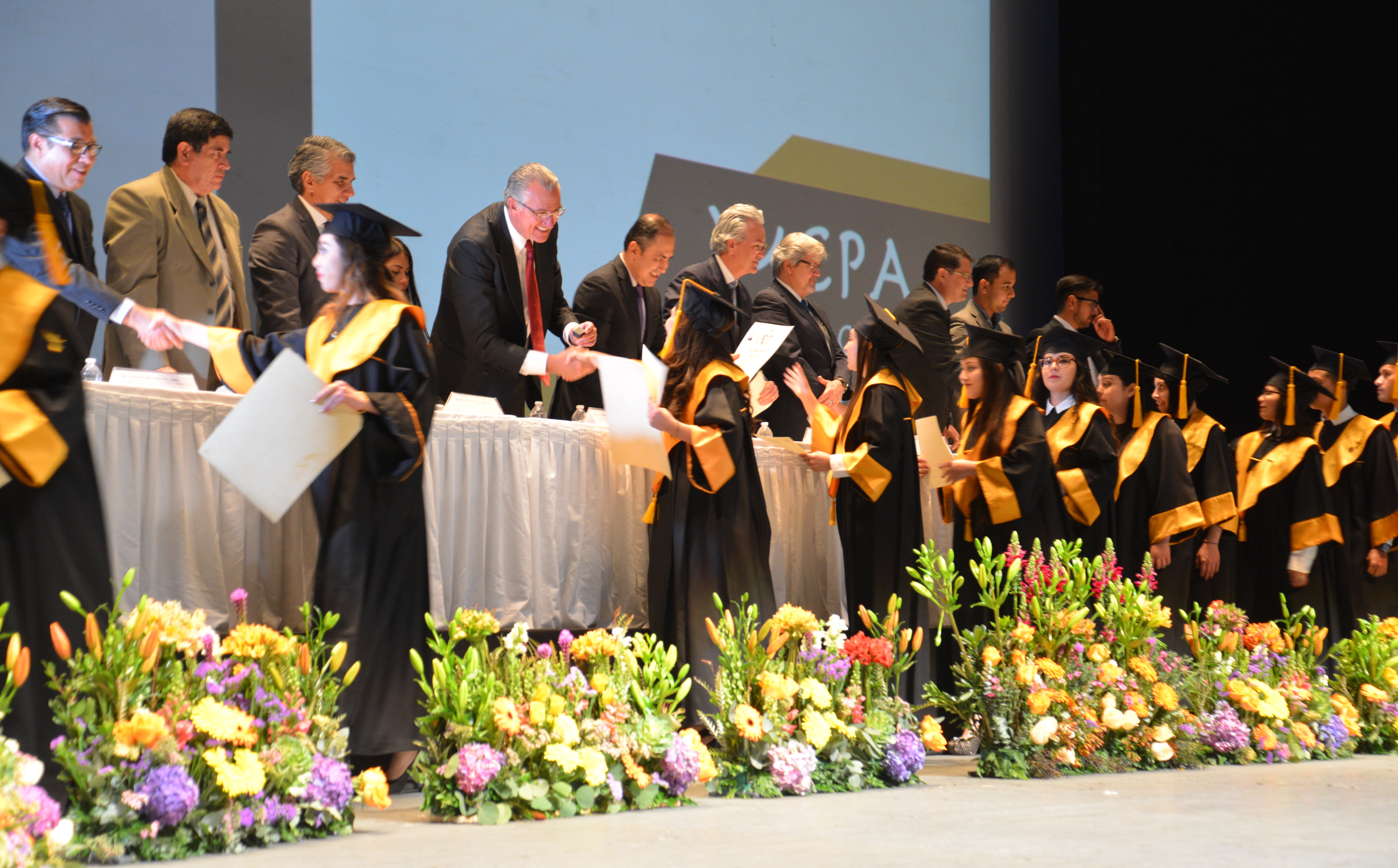 Alumnos graduados recibiendo pergamino