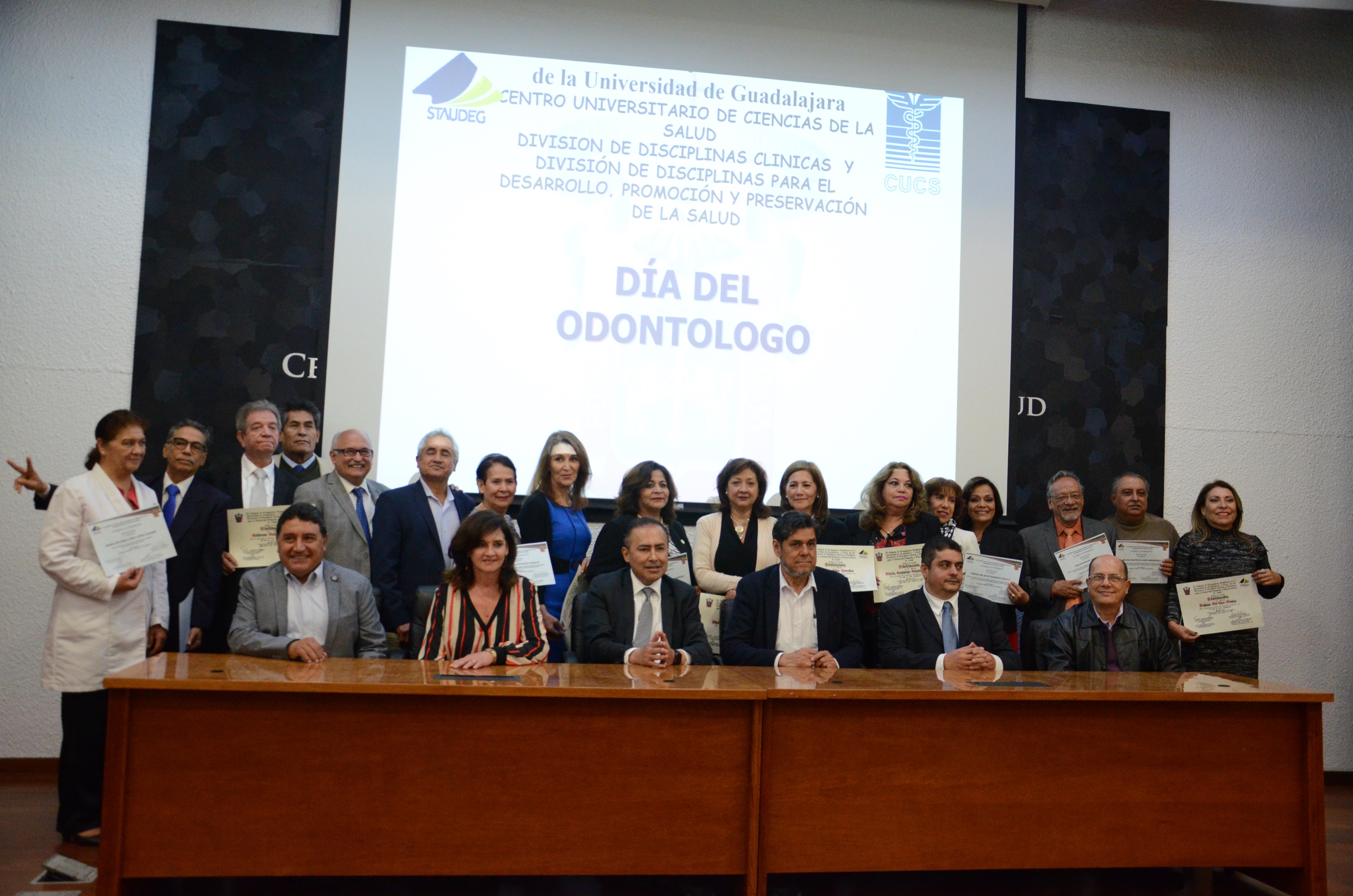 Grupo de odontólogos reconocidos posando para la foto con el rector del CUCS y demás autoridades.