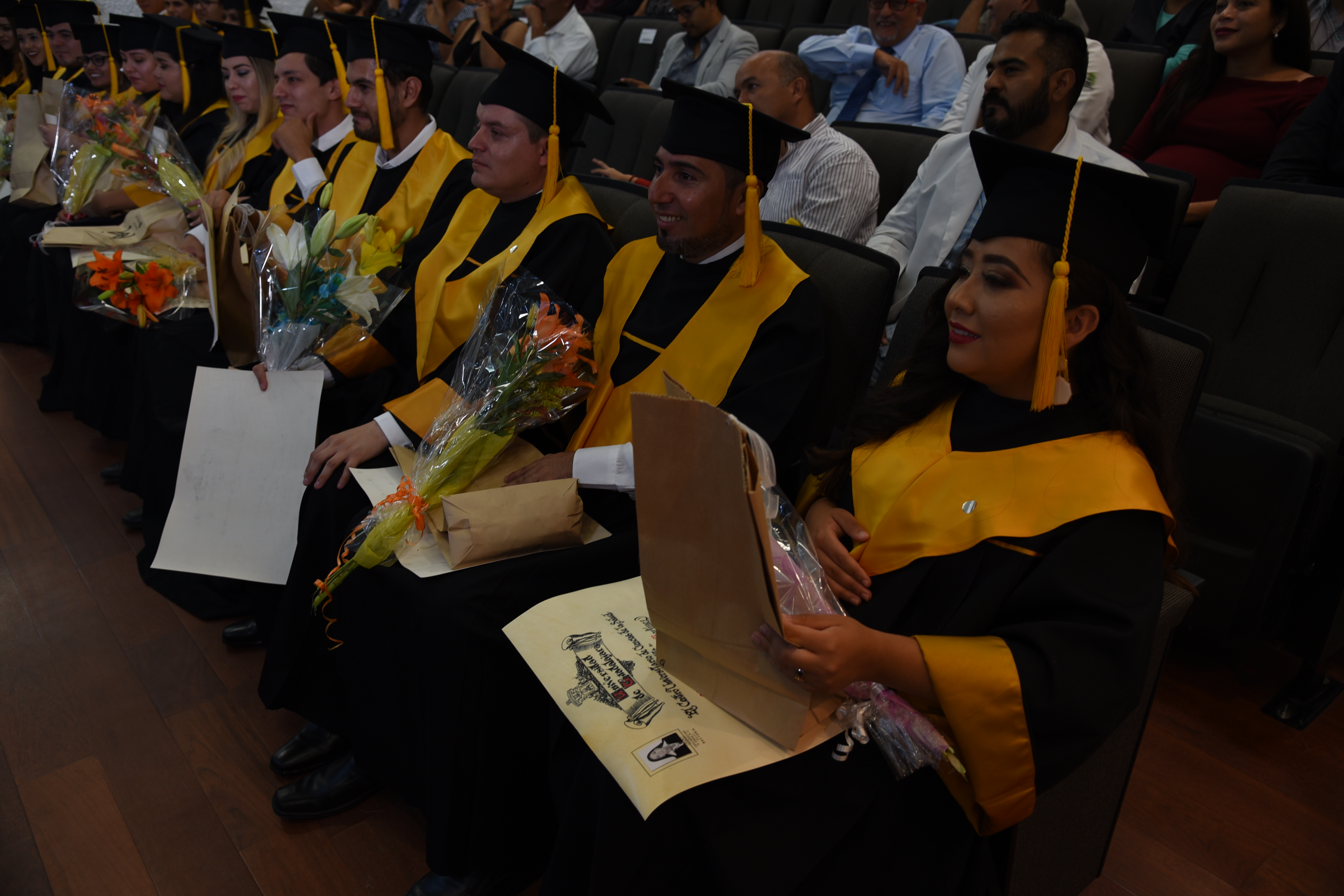 Alumnos graduados escuchando mensajes