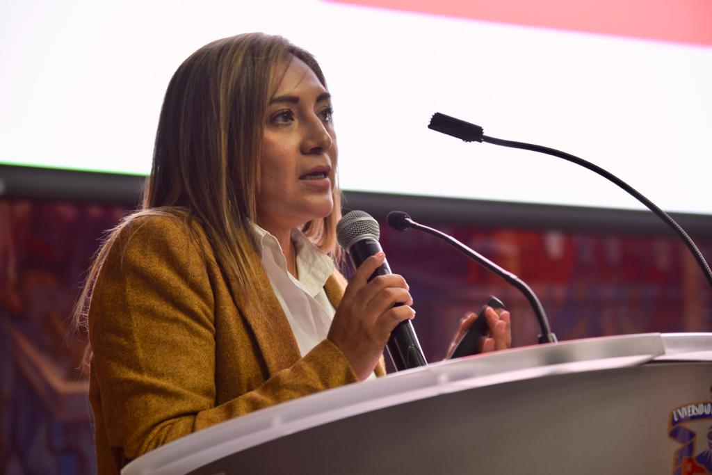 Tercera conferencista durante el conversatorio haciendo uso de la voz en pódium