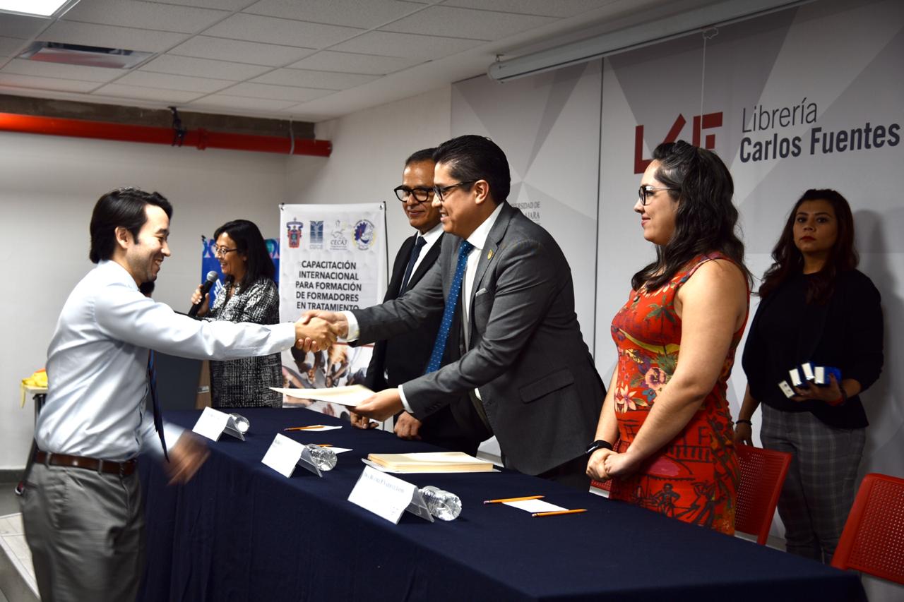 Rector del CUCS entregando reconocimiento a académico graduado