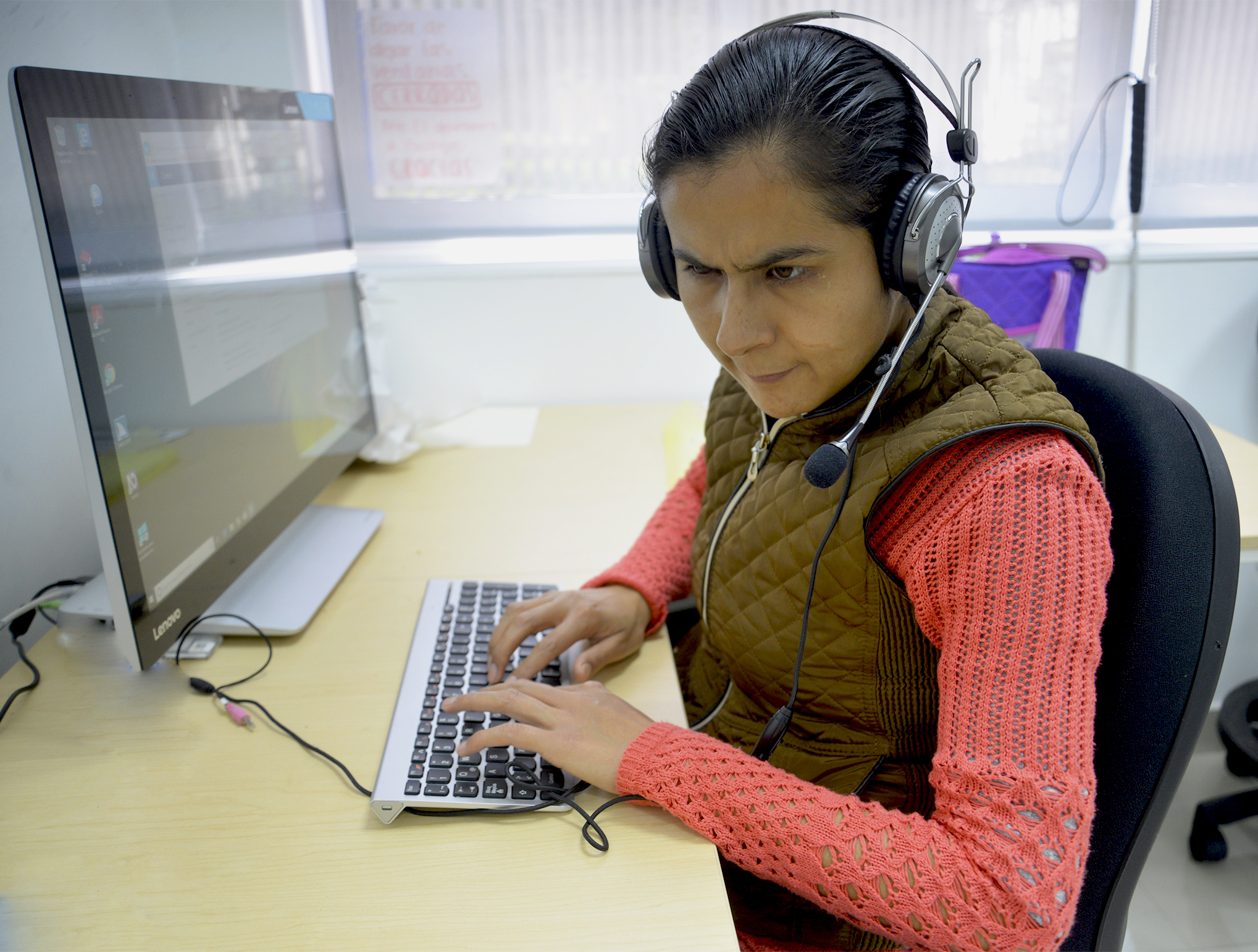 Maribel Flores usando su computadora con uso de audífonos