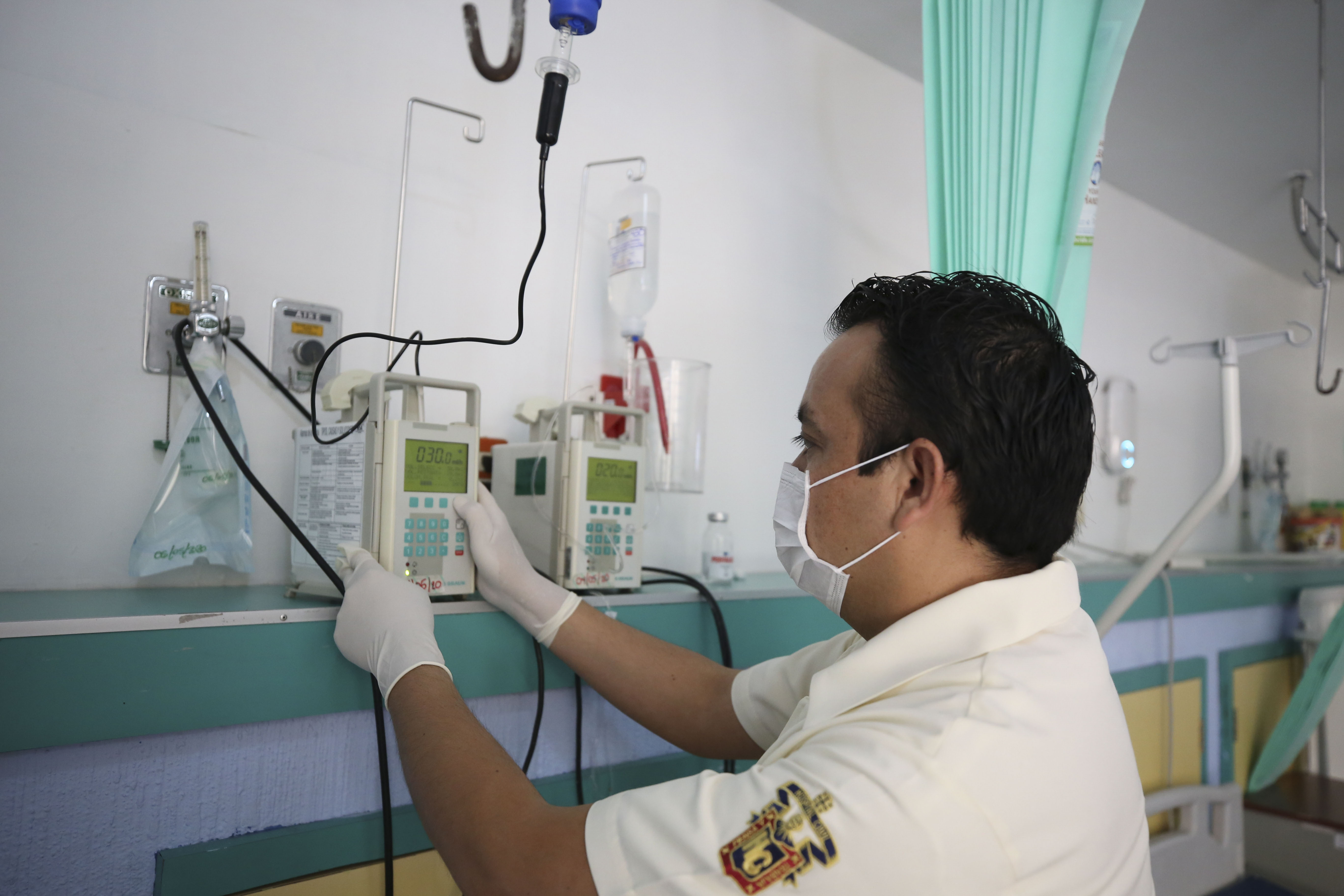 Un enfermero de perfil programando un equipo en la habitación de un hospital