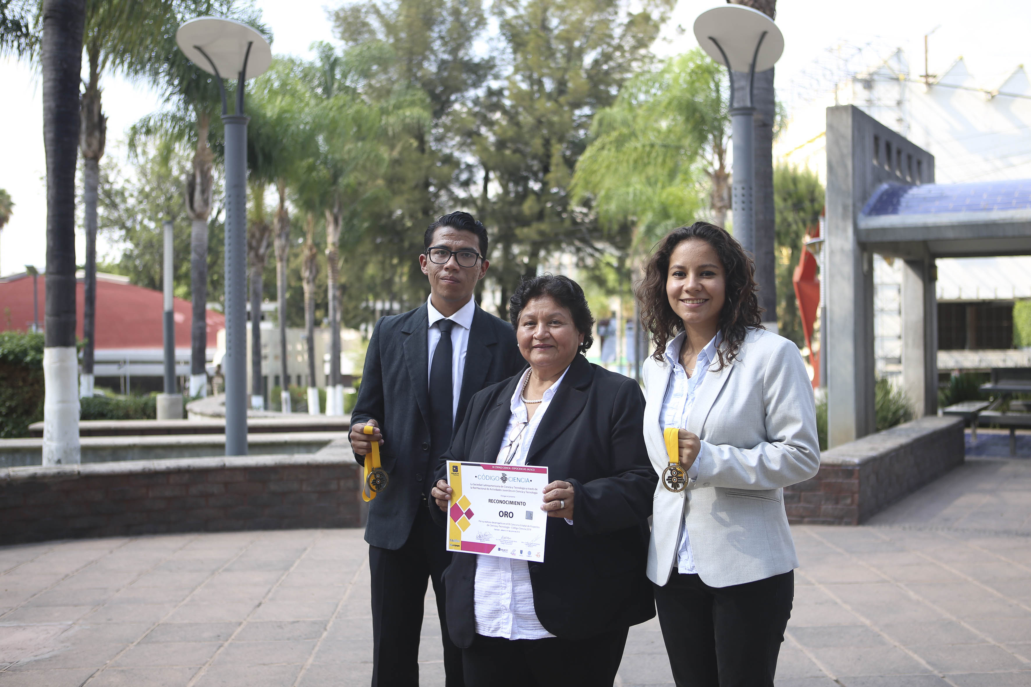 Alumnos ganadores del Oro junto con su asesora exhibiendo el reconocimiento