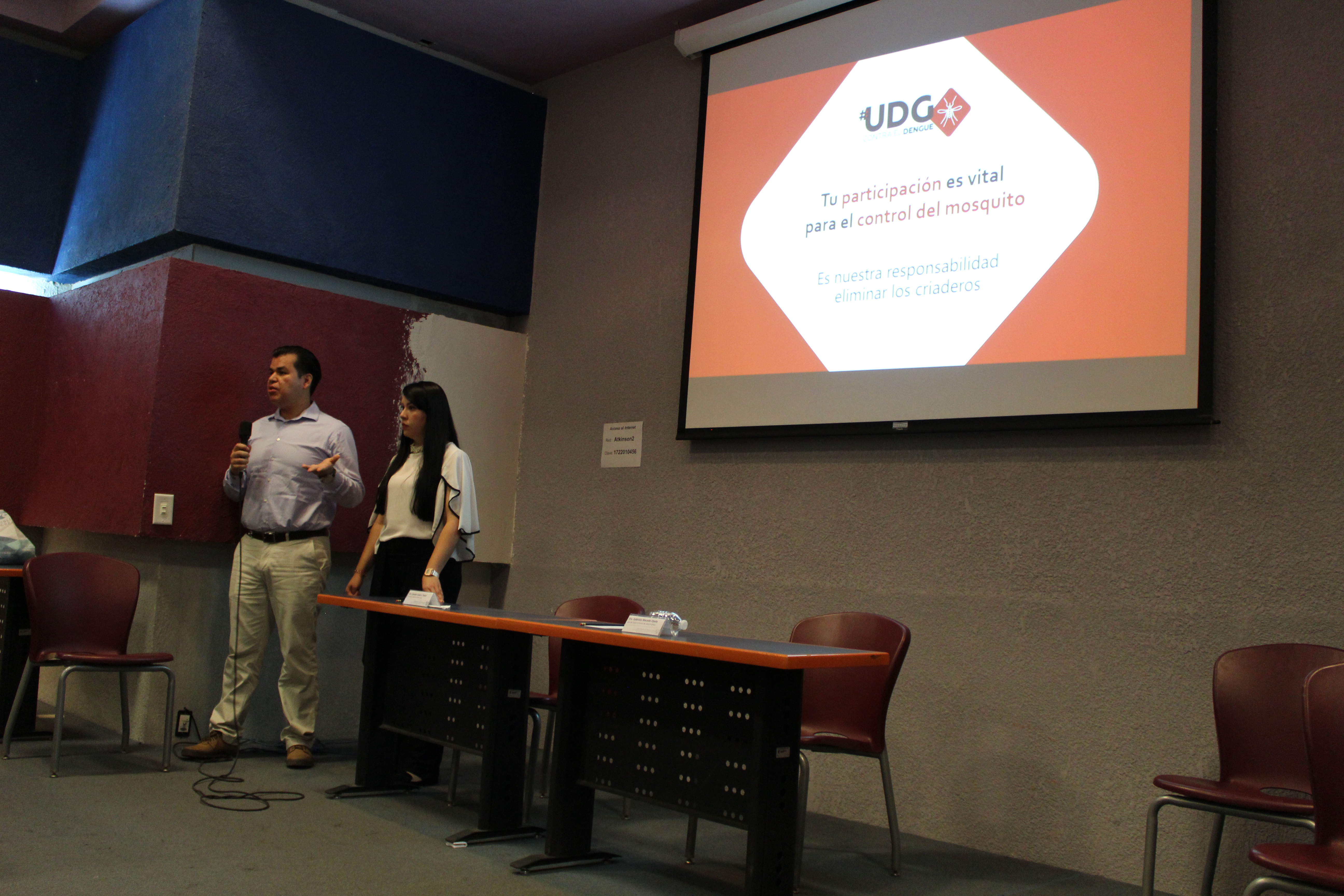 Dos capacitadores, al fondo una diapositiva en la pantalla