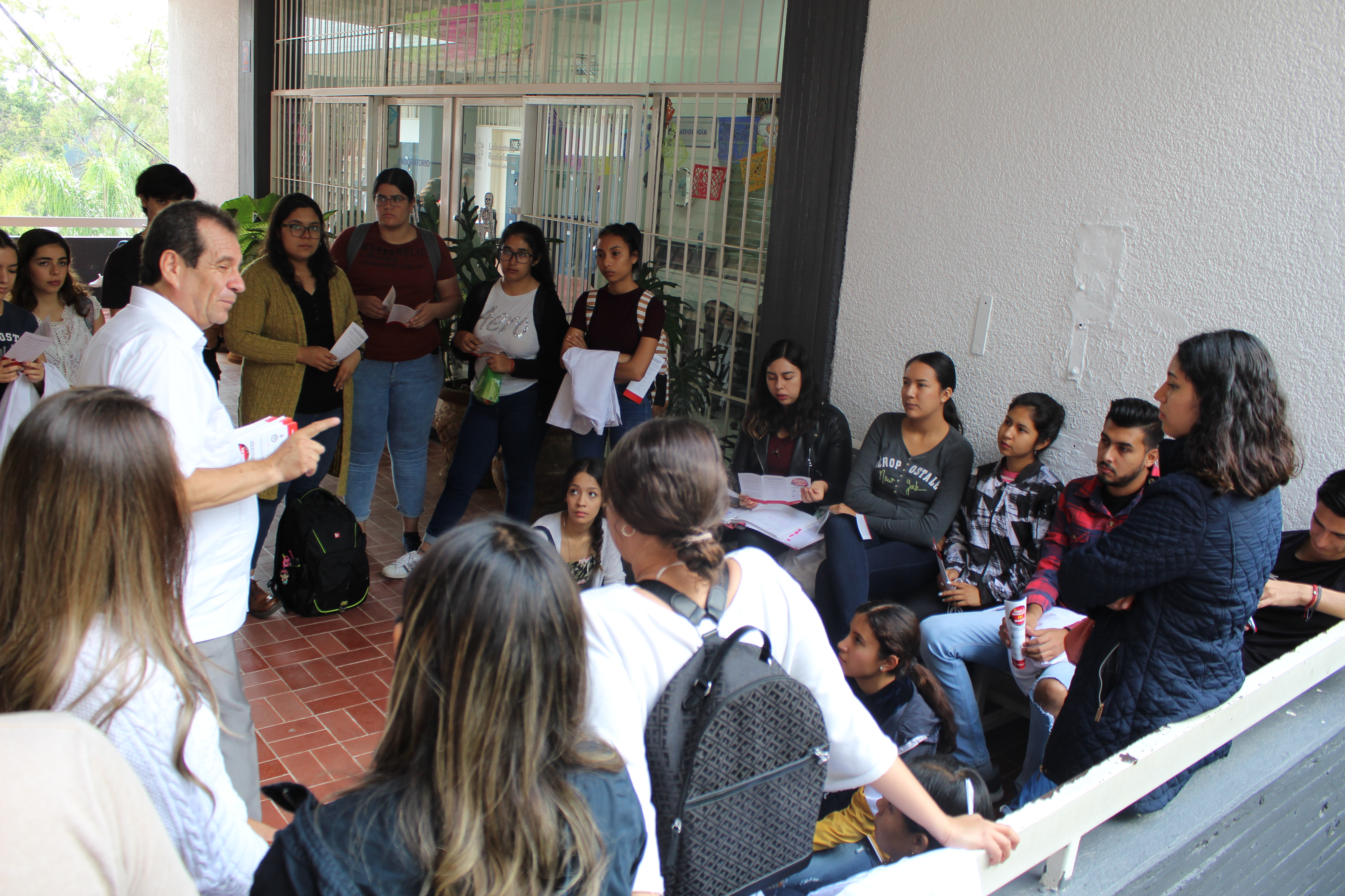 Diputado hablando de su campaña con alumnos sentados en el suelo en uno de los pasillos de Odontología