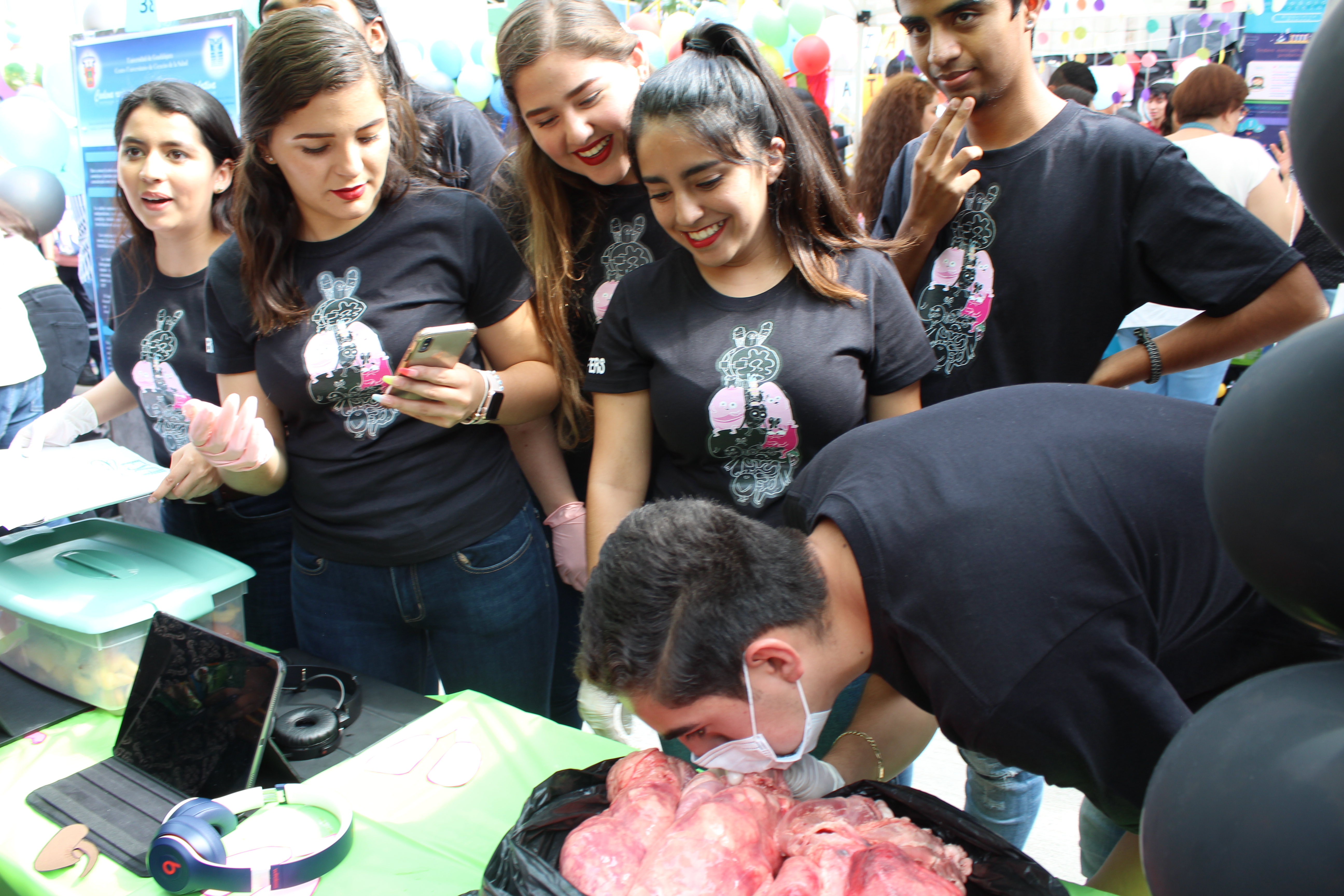 Alumno asistente con tapabocas oliendo un producto cárnico