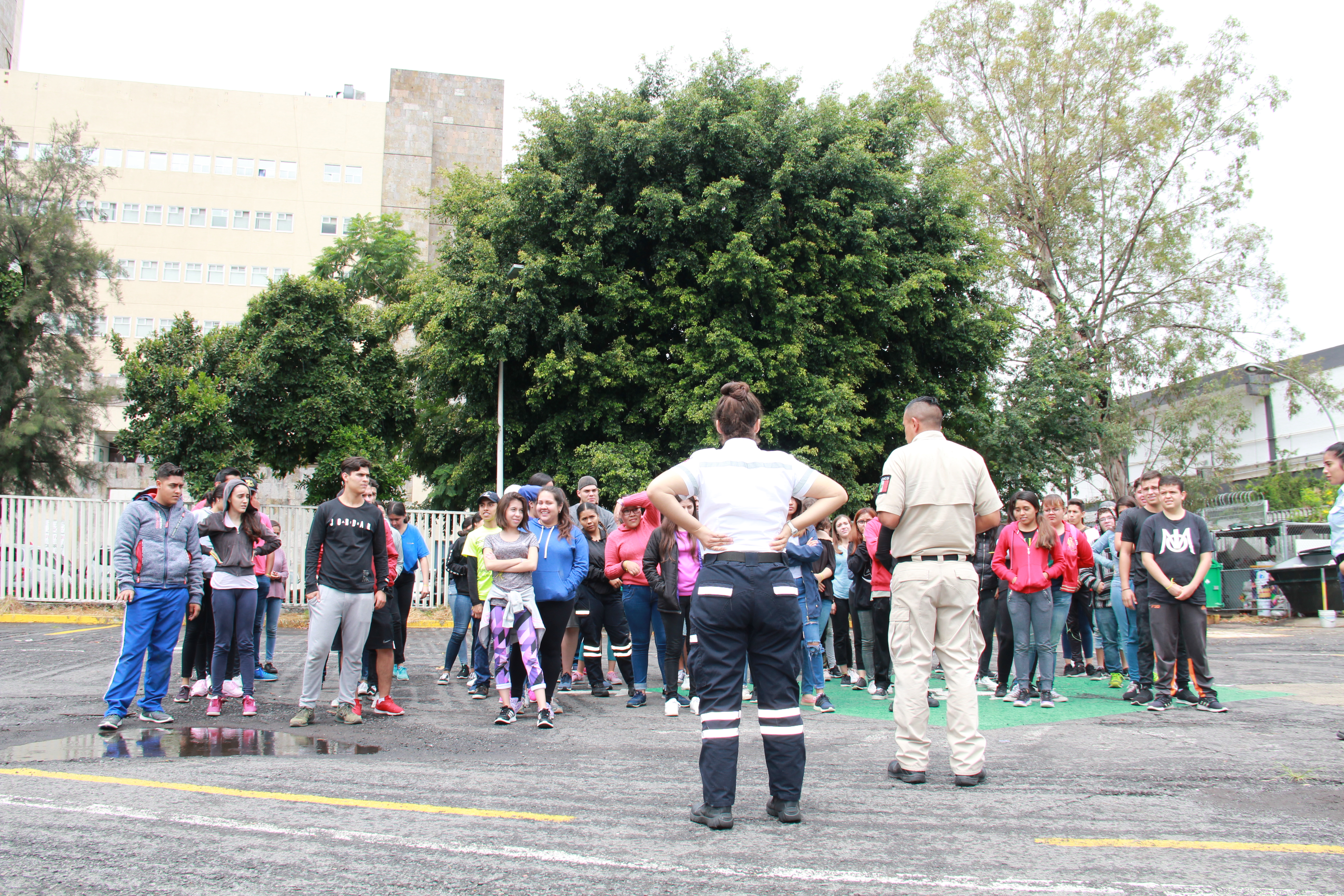 Voluntaria de protección civil organizando a un grupo de estudiantes en uno de los estacionamientos