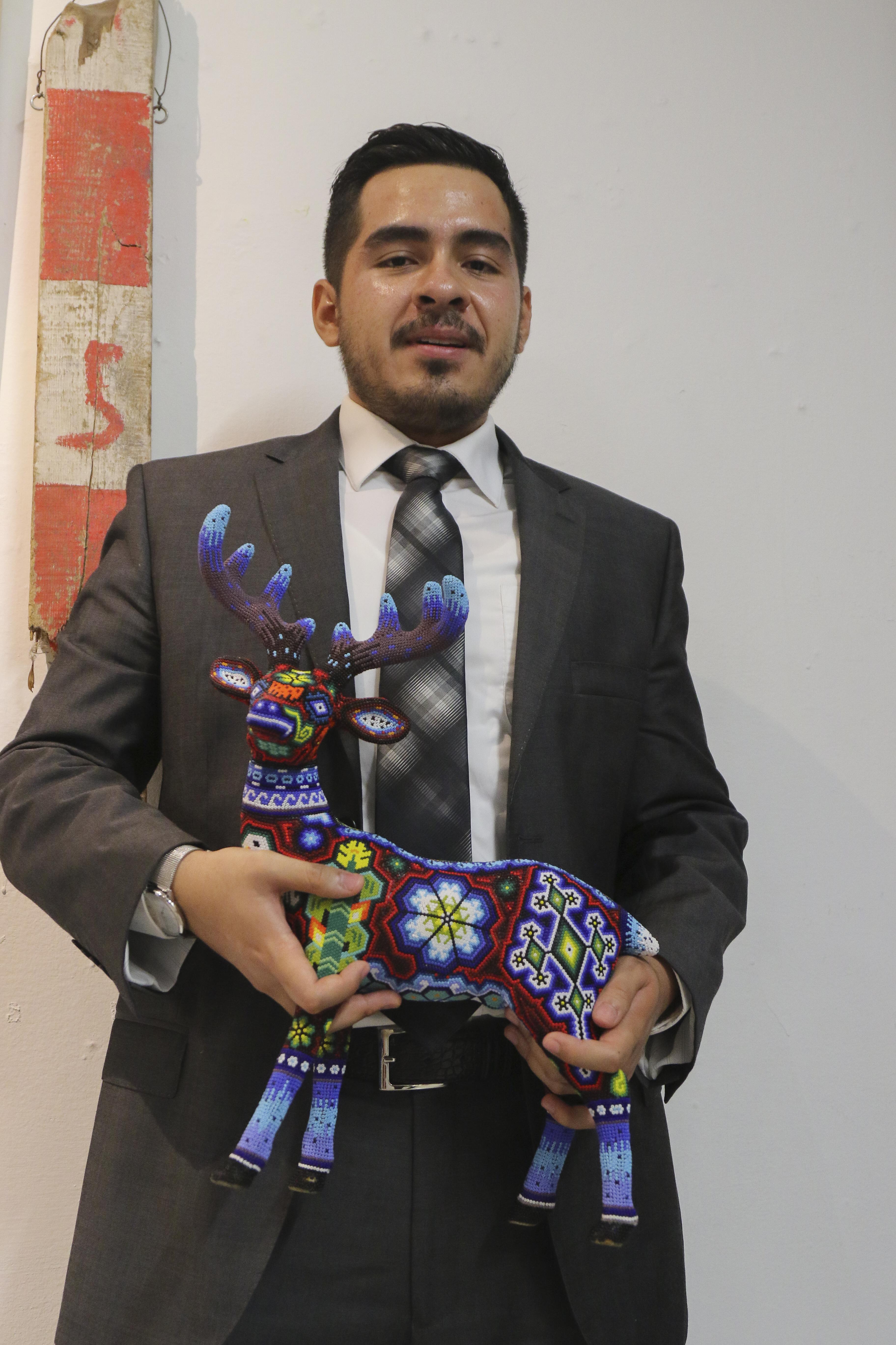 Iván Segura Durán posa para la foto, tiene en las manos la estatuilla artesanal con la que lo distinguieron