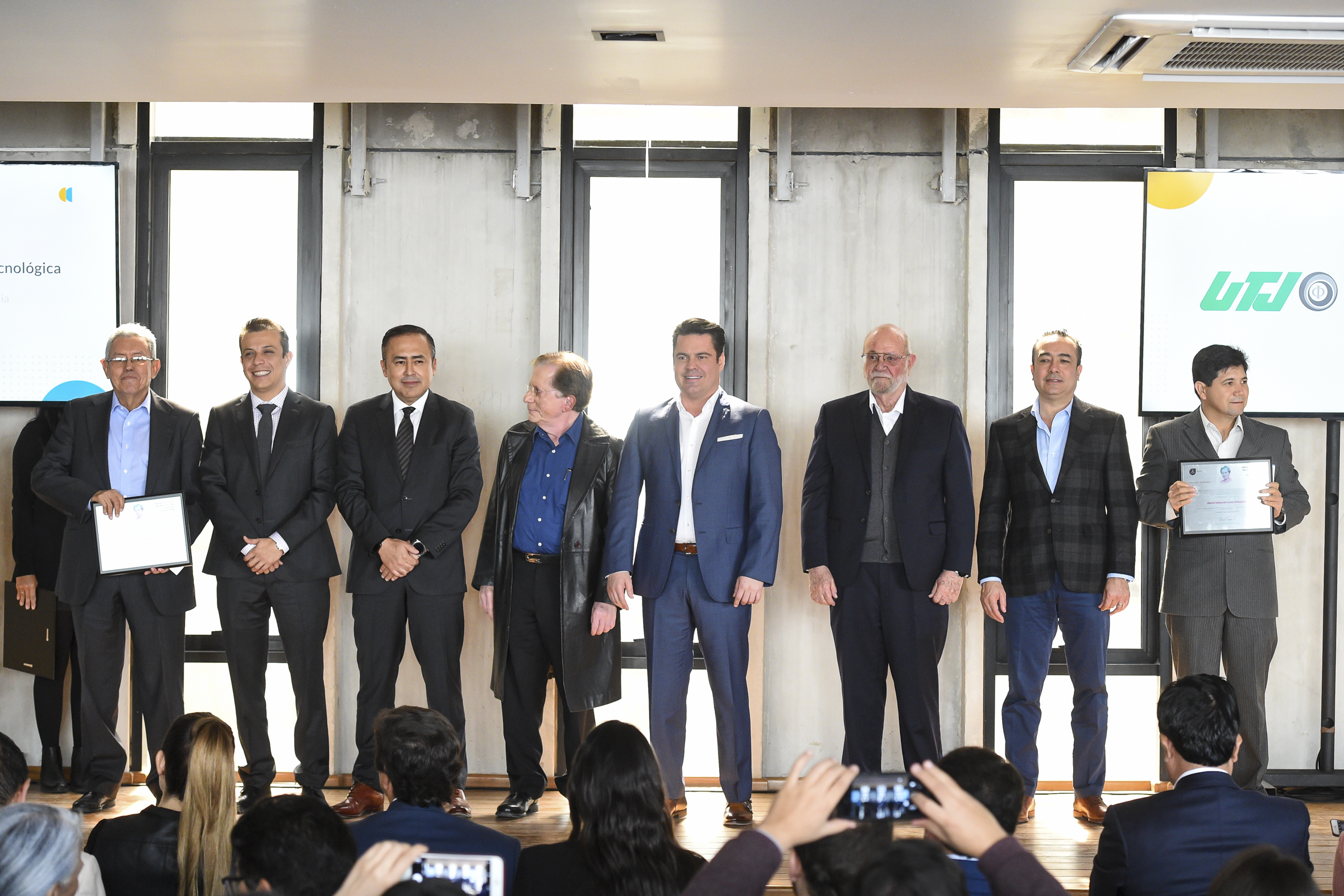 Funcionarios de Gobierno posando para la foto con dos galardonados de UdeG