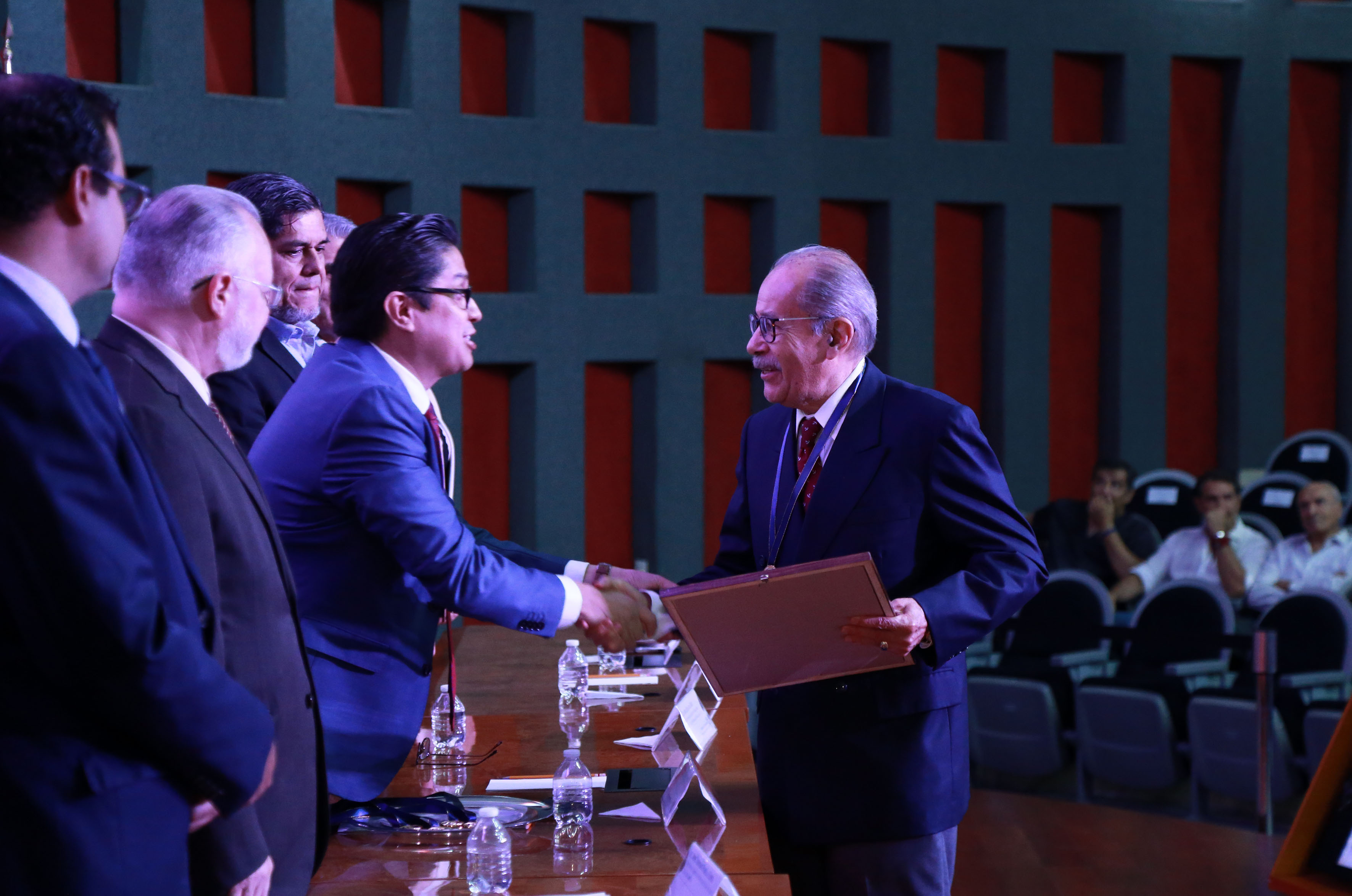 Galardonado recibiendo reconocimiento y medalla de manos del rector