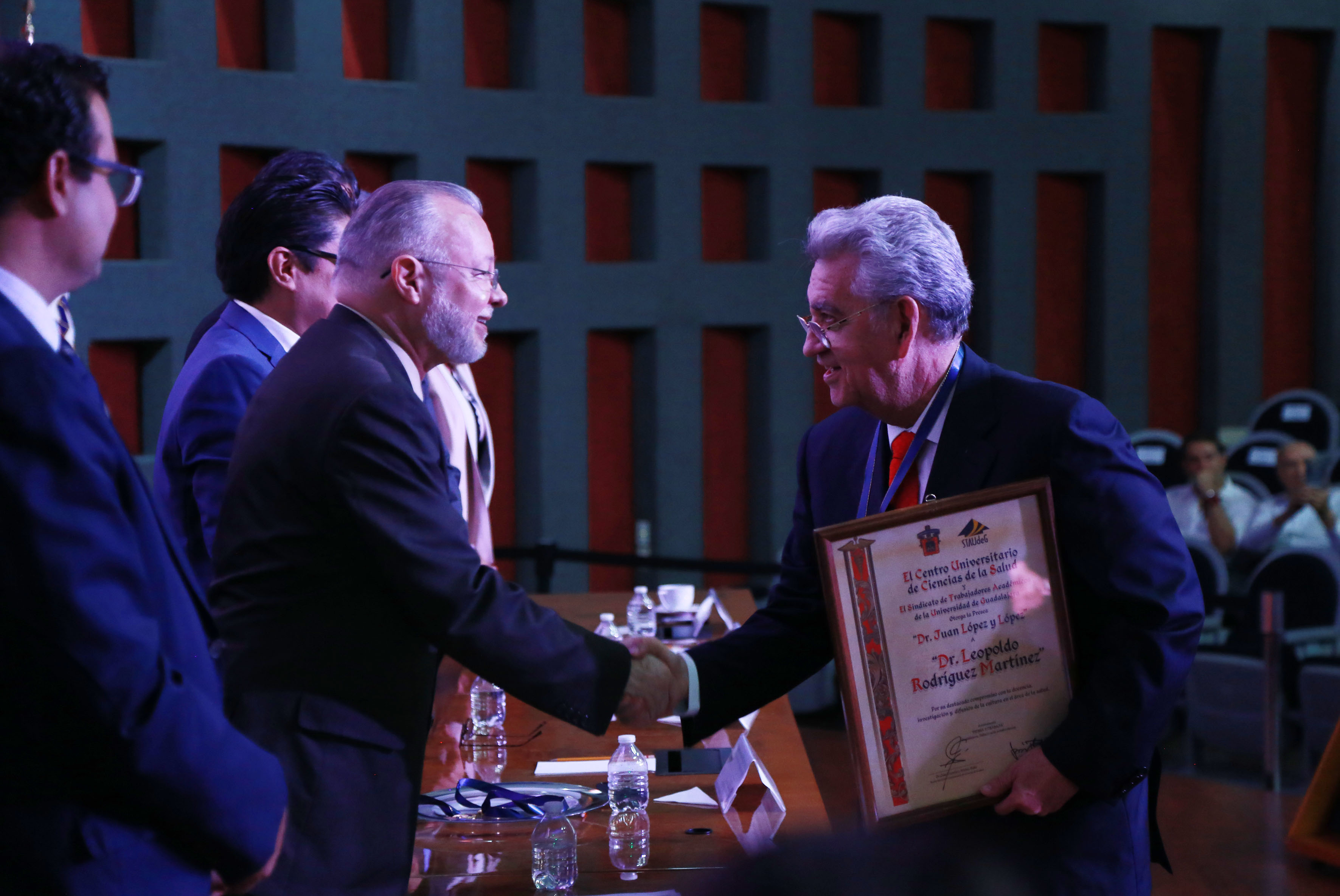 Galardonado recibiendo reconocimiento y medalla de manos del Mtro. Trinidad Padilla López