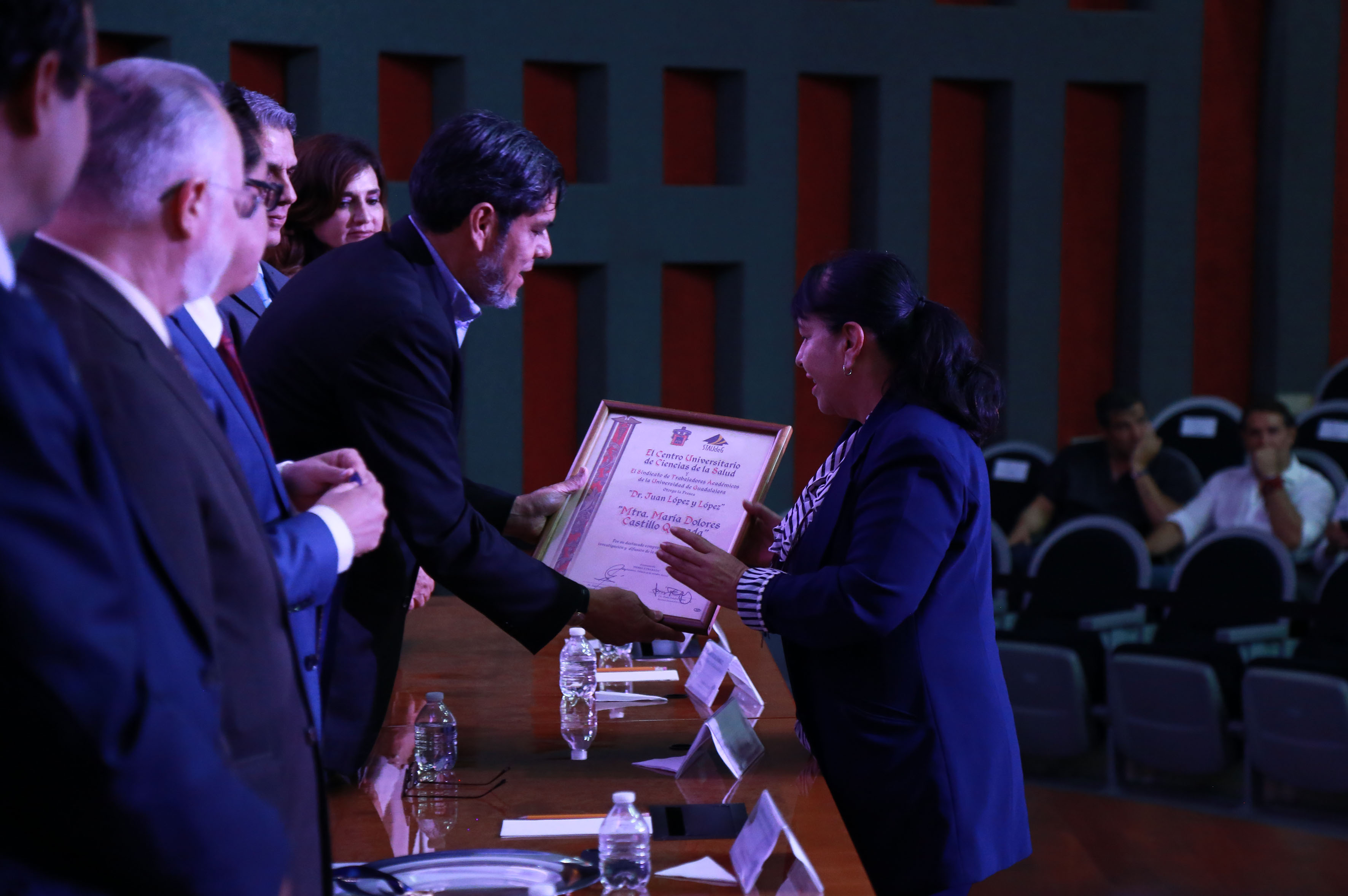 Galardonada recibiendo reconocimiento y medalla de manos del secretario general de STAudeG