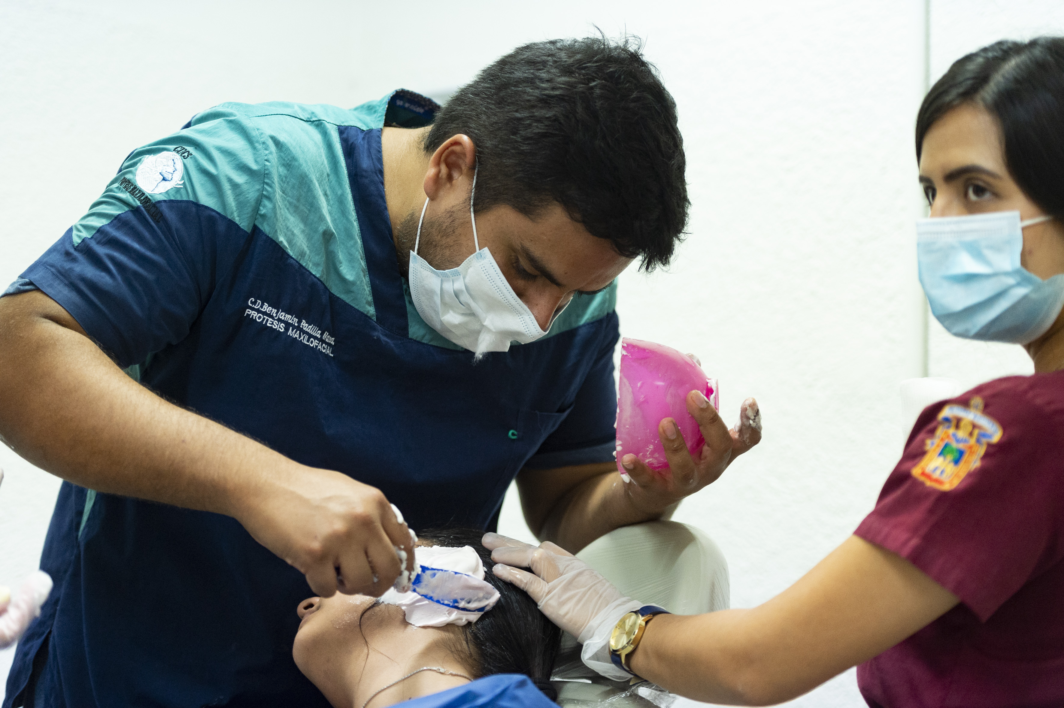 Estudiantes de especialidad tomando muestra de la oreja de una paciente