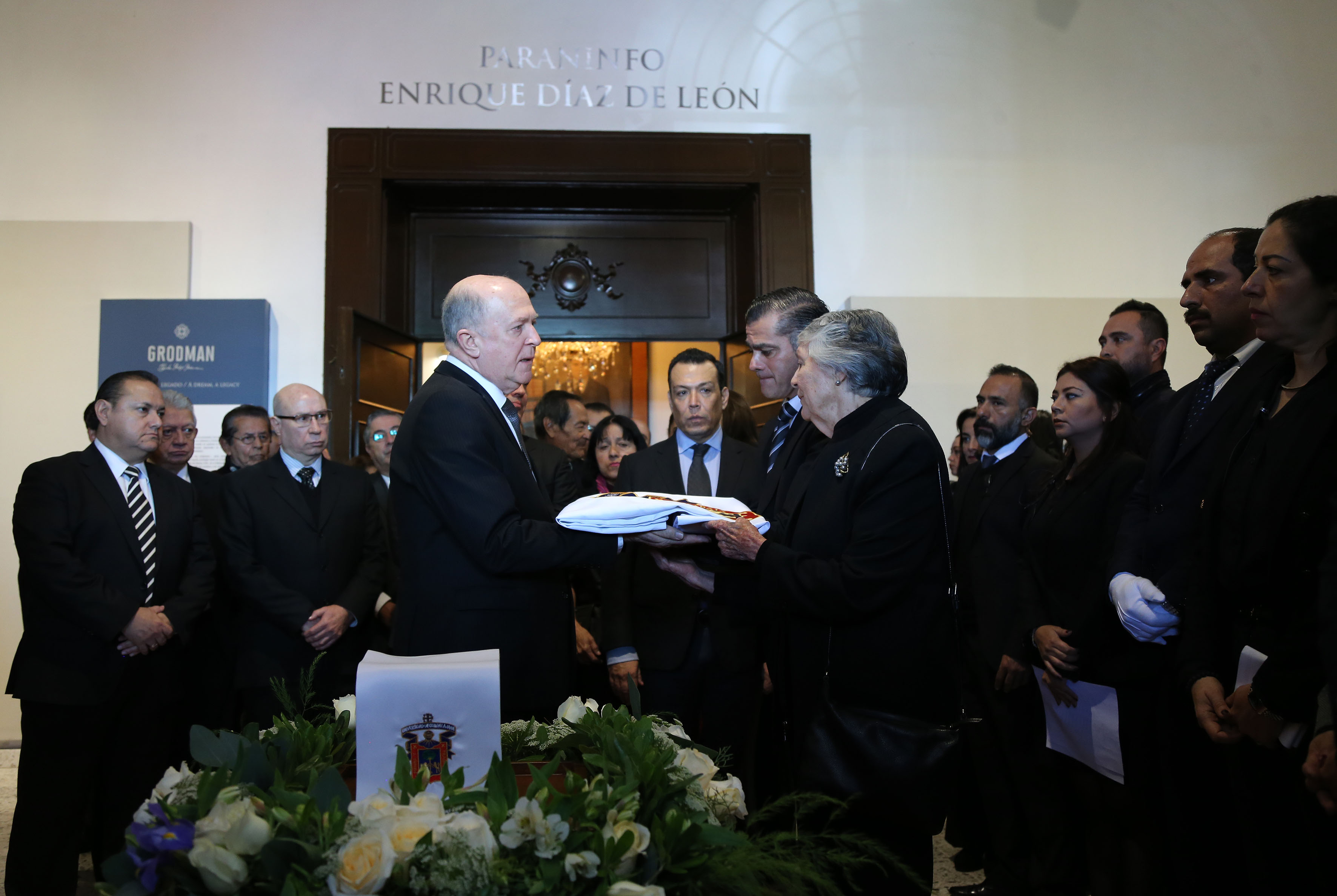 Rector General haciendo entrega de la bandera de la UdeG a la viuda del Dr. Mario Rivas S.