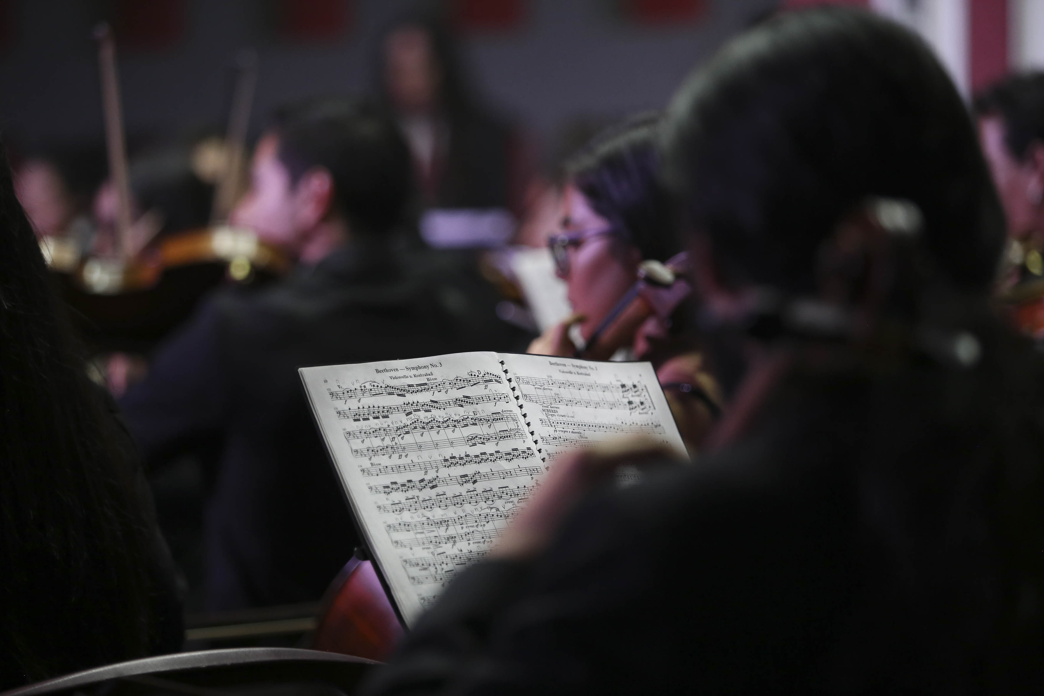 Partitura abierta en primer plano y al fondo músicos tocando