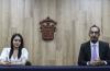 Foto de los dos premiados de CUCS, al fondo el escudo de la UdeG