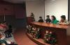 Toma de lado, miembros del presídium y al fondo en el pódium la ponente