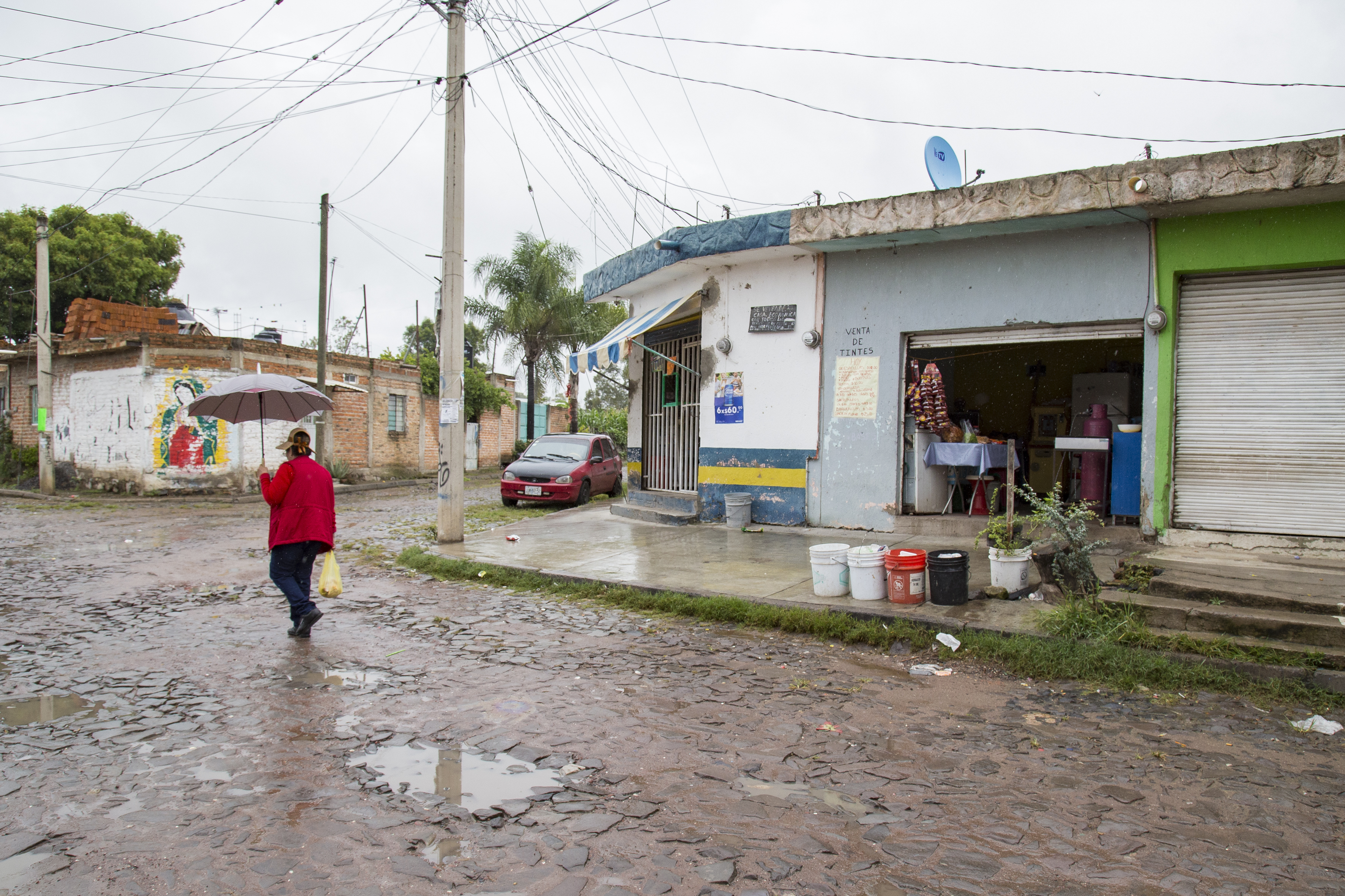 Señora caminando bajo la lluvia en una colonia de El Salto