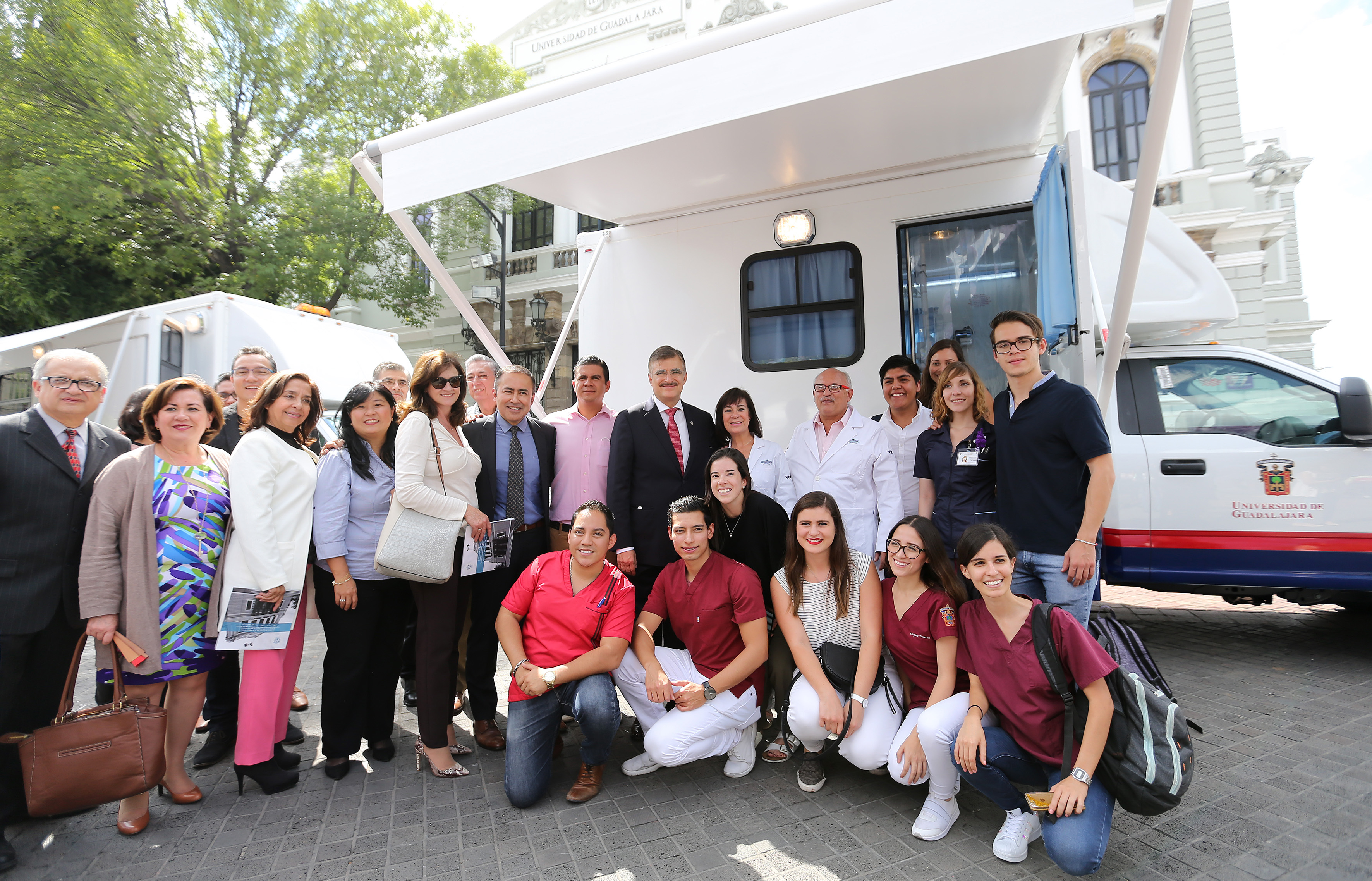 Colaboradores del CUCS posando con el rector del Centro y el Rector General al pie de una de las unidades móviles