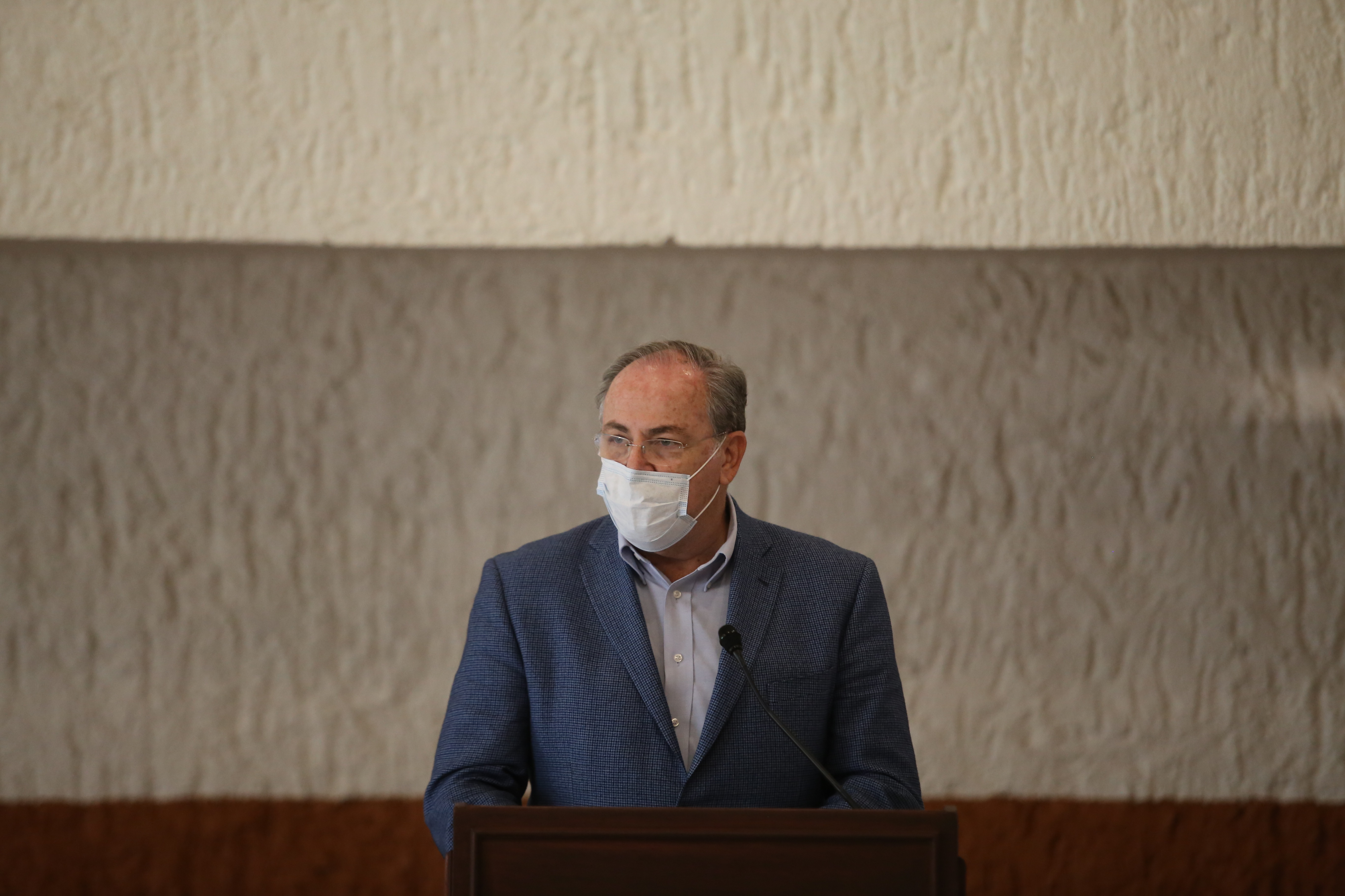 Secretario de Salud al micrófono en el pódium durante rueda de prensa virtual